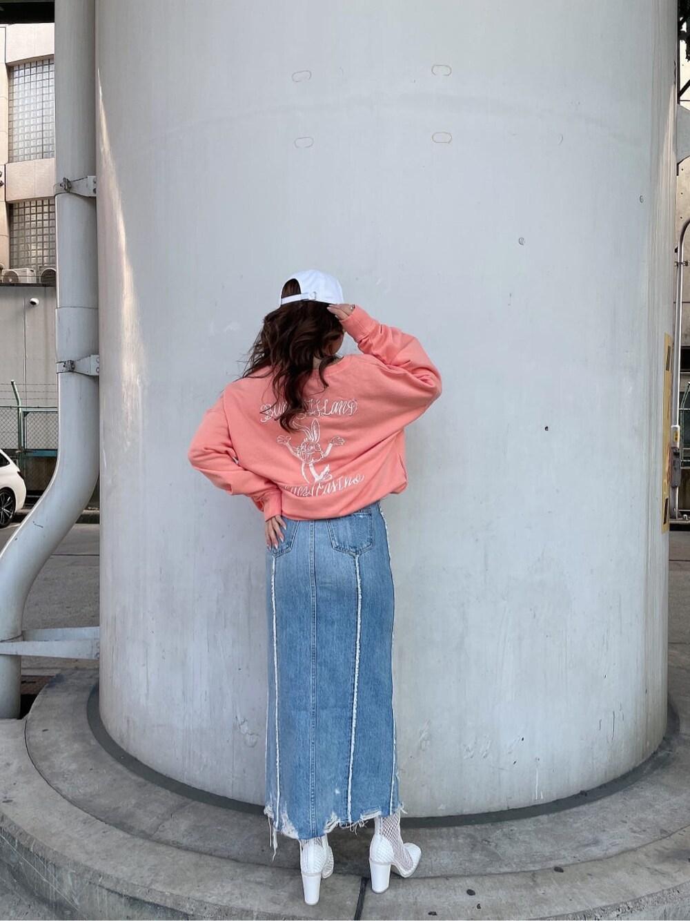 ホワイト系のブーツ、オレンジ系のスウェット、ブルー系のデニムスカートを着用したレディースの冬コーディネートの4枚目の写真