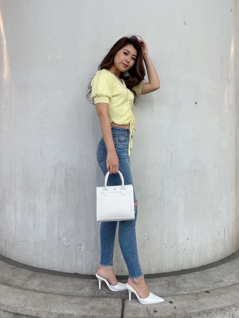 ホワイト系のパンプス、ホワイト系のハンドバッグ、ブルー系のデニムパンツを着用したレディースの春コーディネートの2枚目の写真