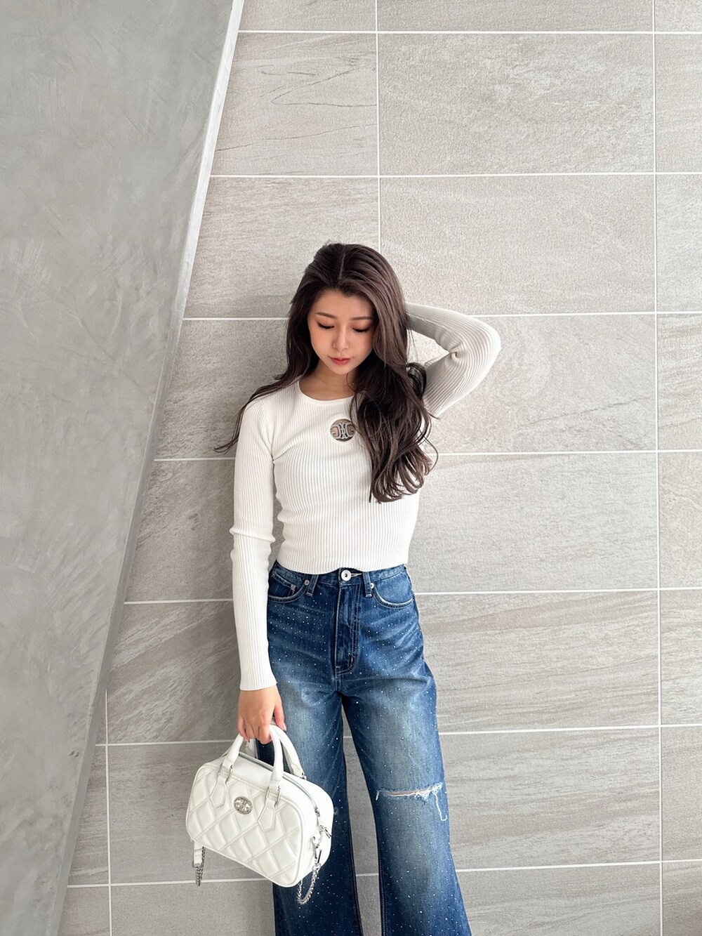 ブルー系のデニムパンツ、ホワイト系のパンプス、ホワイト系のハンドバッグを着用したレディースの冬コーディネートの4枚目の写真