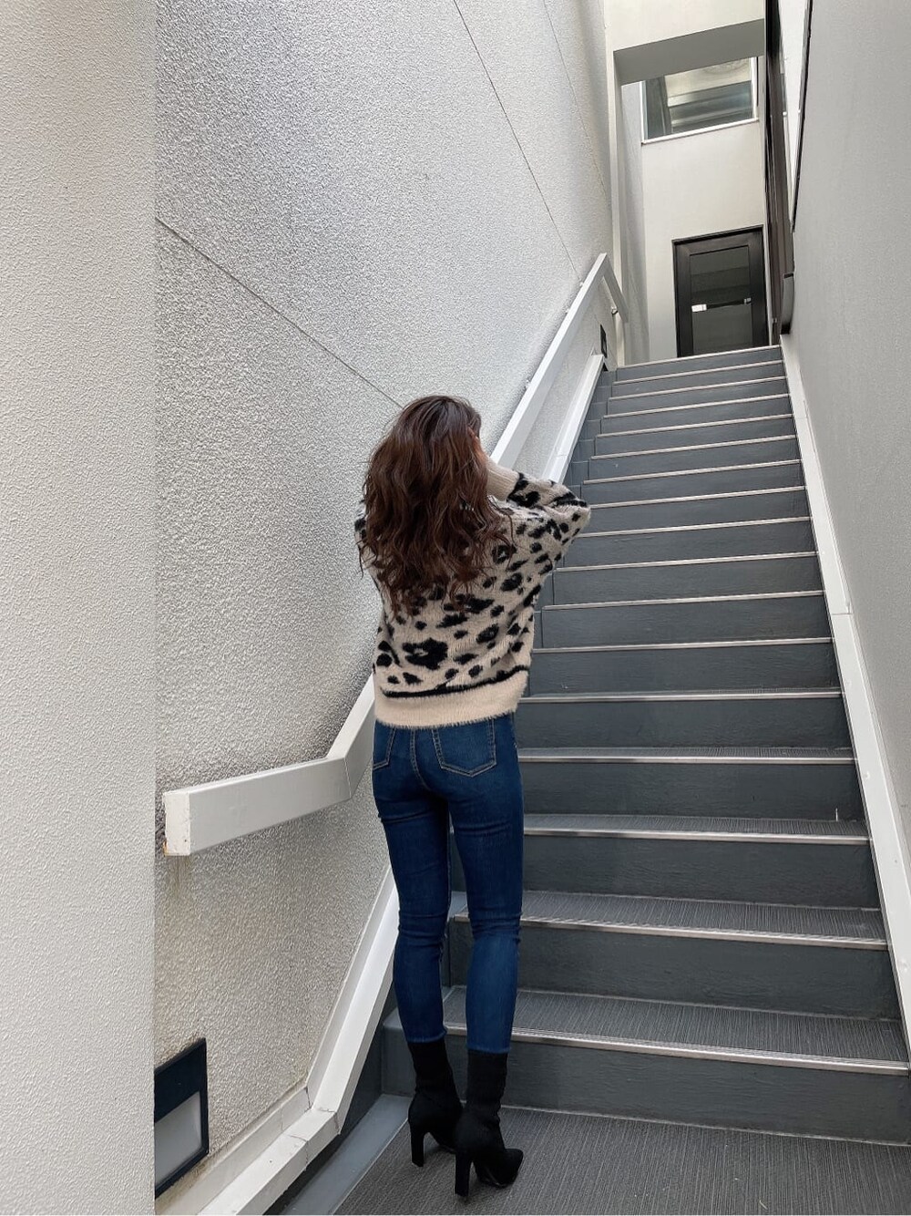 ホワイト系のニット/セーター、ブルー系のデニムパンツ、ブラック系のブーツを着用したレディースの秋コーディネートの6枚目の写真