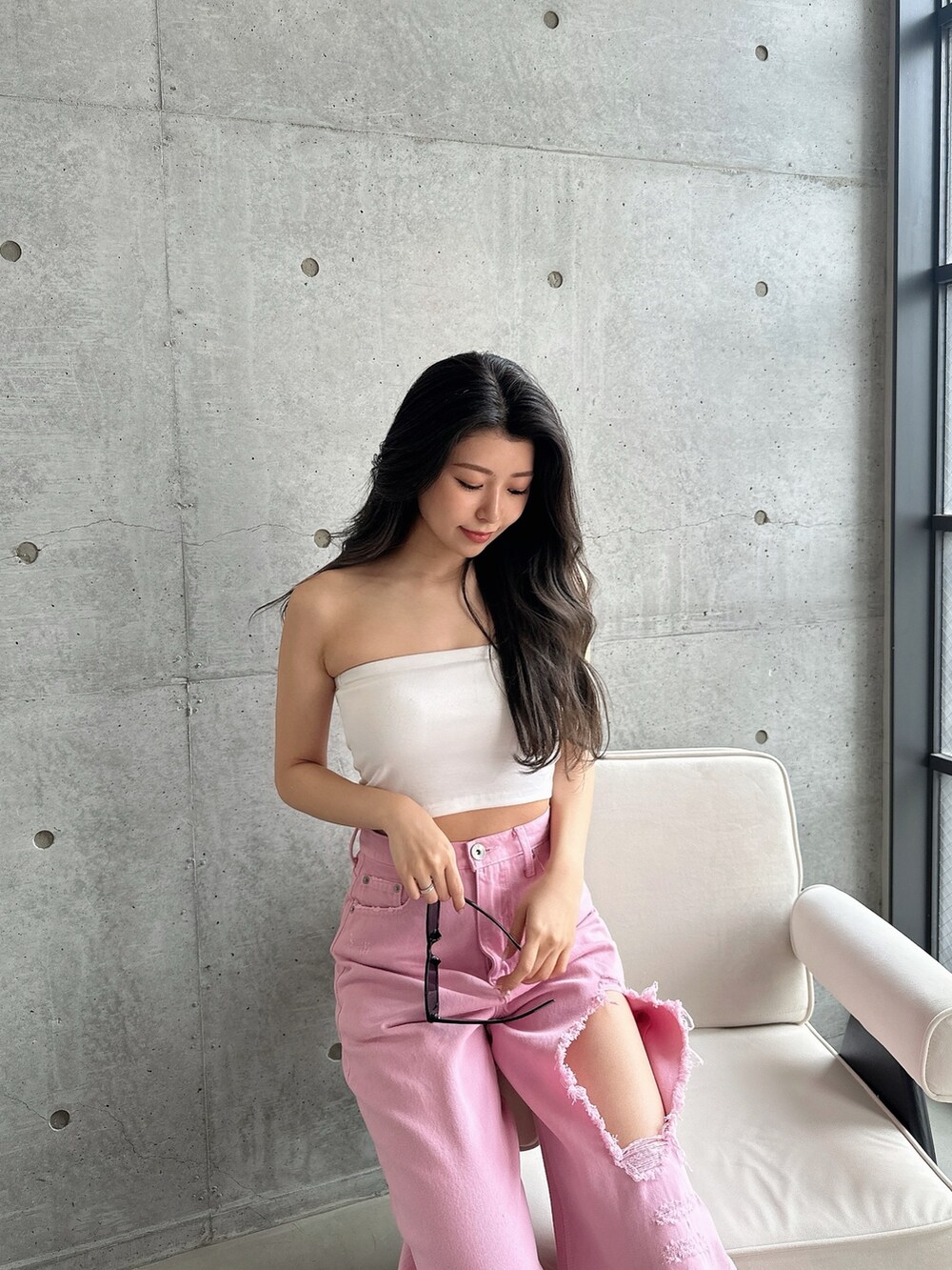 ピンク系のデニムパンツ、ホワイト系のパンプス、ホワイト系のチューブトップを着用したレディースの夏コーディネートの6枚目の写真