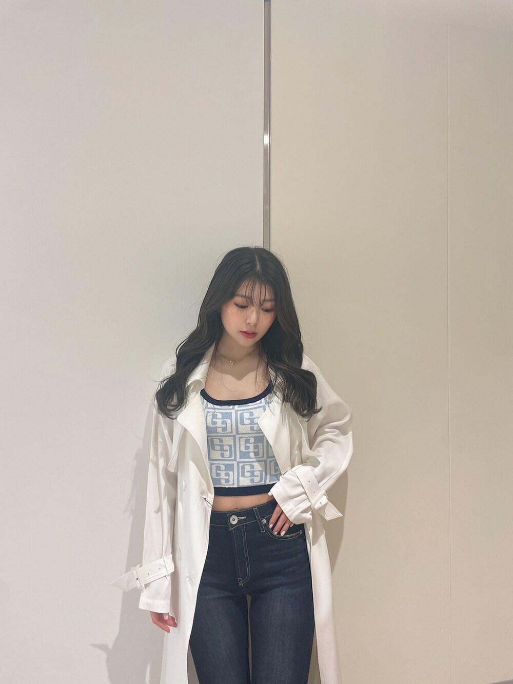 ブルー系のニット/セーター、ホワイト系のトレンチコート、ブルー系のデニムパンツを着用したレディースの春コーディネートの5枚目の写真