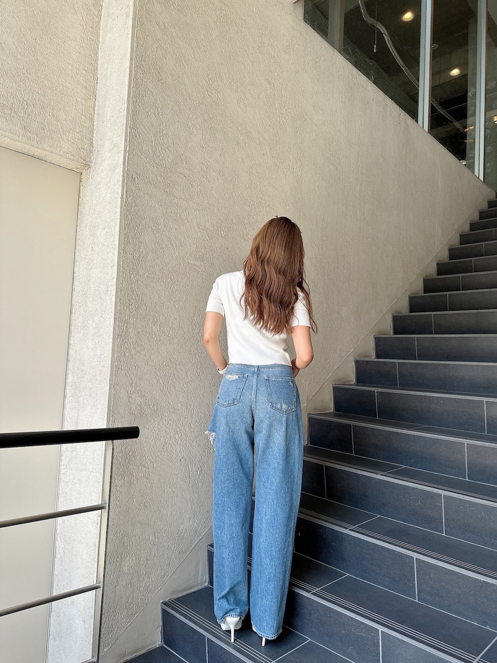 ホワイト系のニット/セーター、ブルー系のデニムパンツ、ブラック系のパンプスを着用したレディースの夏コーディネートの3枚目の写真