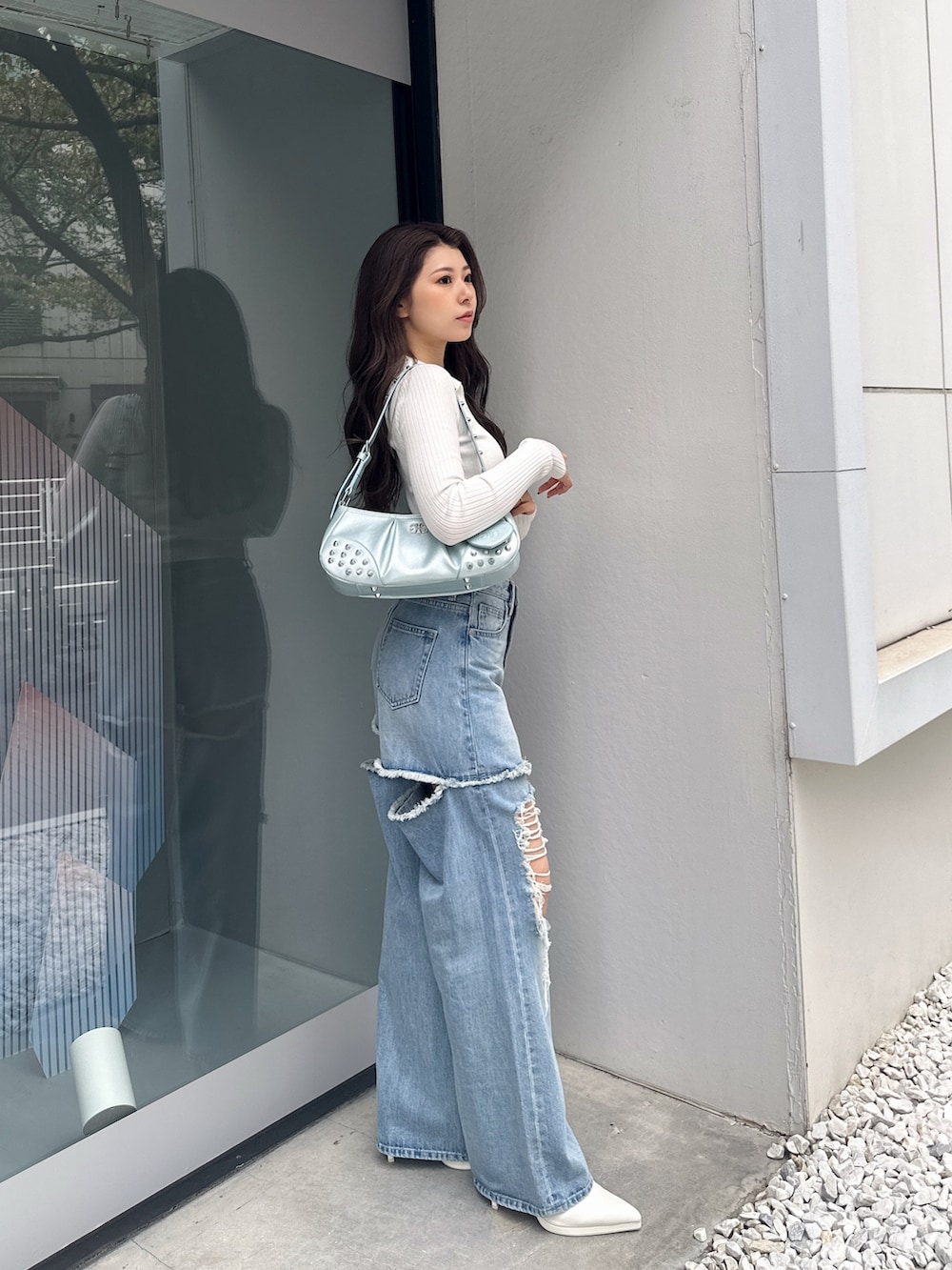 ホワイト系のパンプス、ブルー系のハンドバッグ、ホワイト系のニット/セーターを着用したレディースの冬コーディネートの2枚目の写真