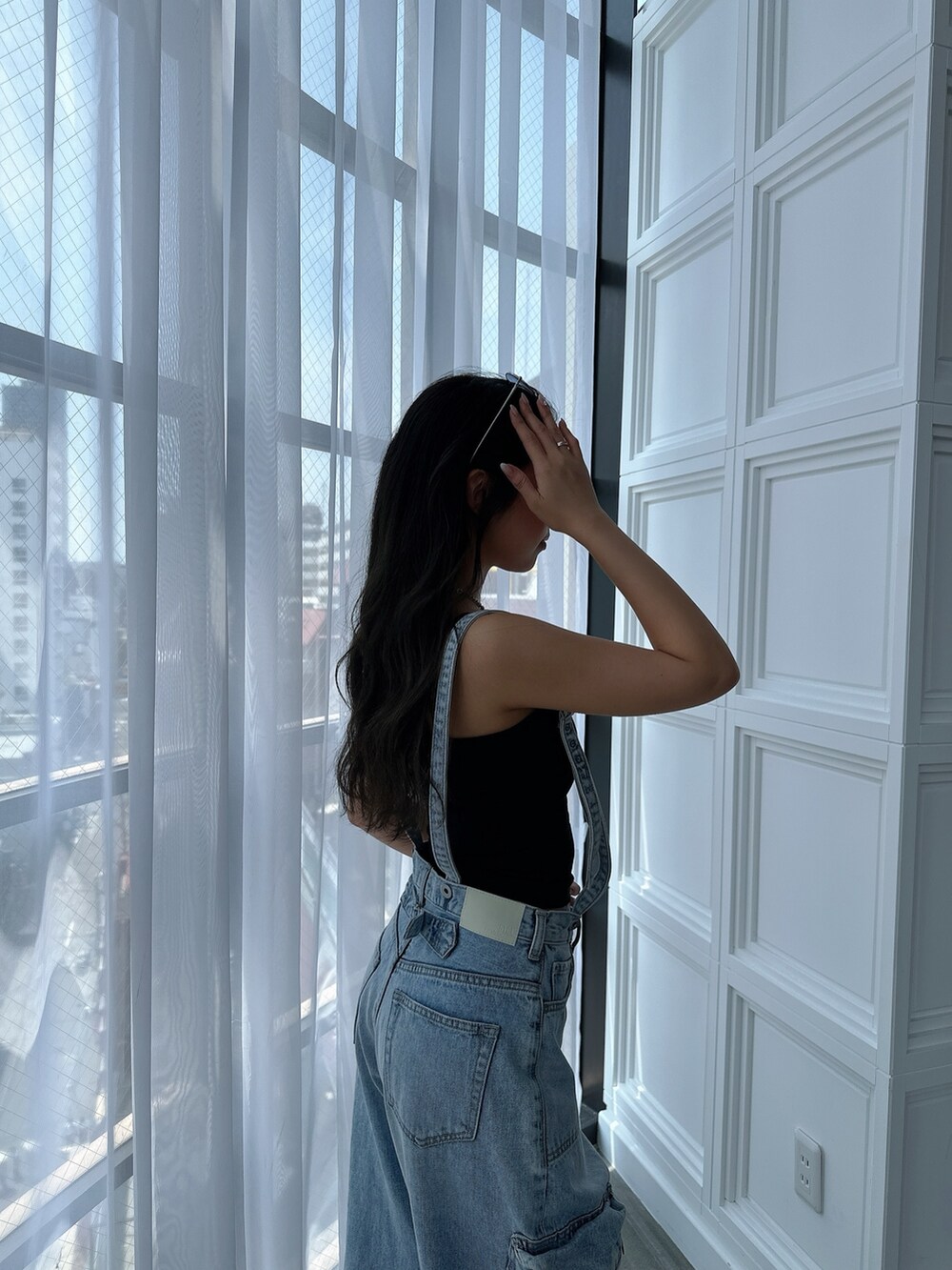 ブラック系のキャミソール、ブルー系のデニムパンツ、ブラック系のサンダルを着用したレディースの夏コーディネートの6枚目の写真