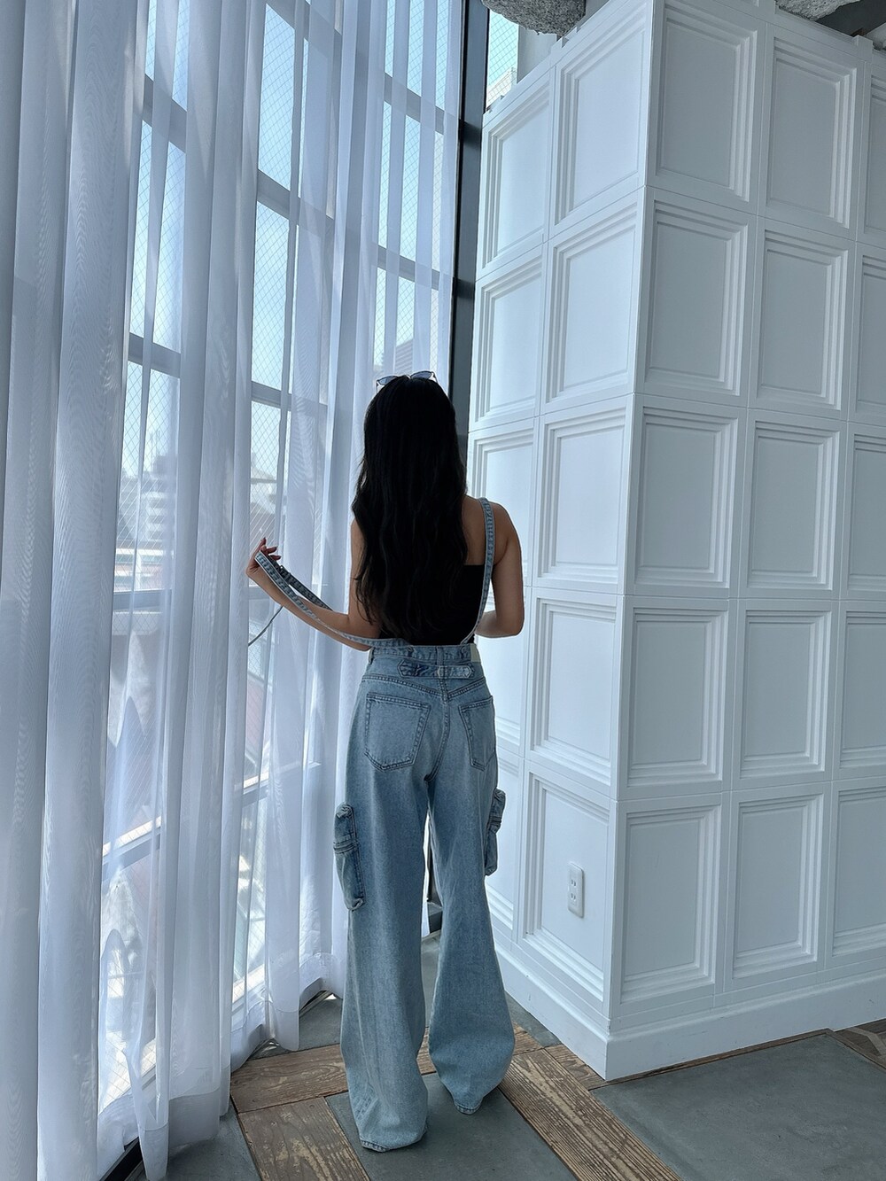 ブラック系のキャミソール、ブルー系のデニムパンツ、ブラック系のサンダルを着用したレディースの夏コーディネートの2枚目の写真