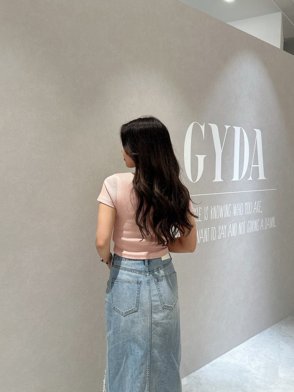 ブルー系のデニムスカート、ホワイト系のサンダル、ピンク系のTシャツ/カットソーを着用したレディースの春コーディネートの4枚目の写真