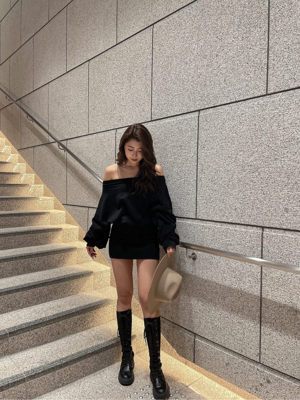 ブラック系のワンピース、ブラック系のブーツ、ベージュ系のハットを着用したレディースの秋コーディネートの3枚目の写真