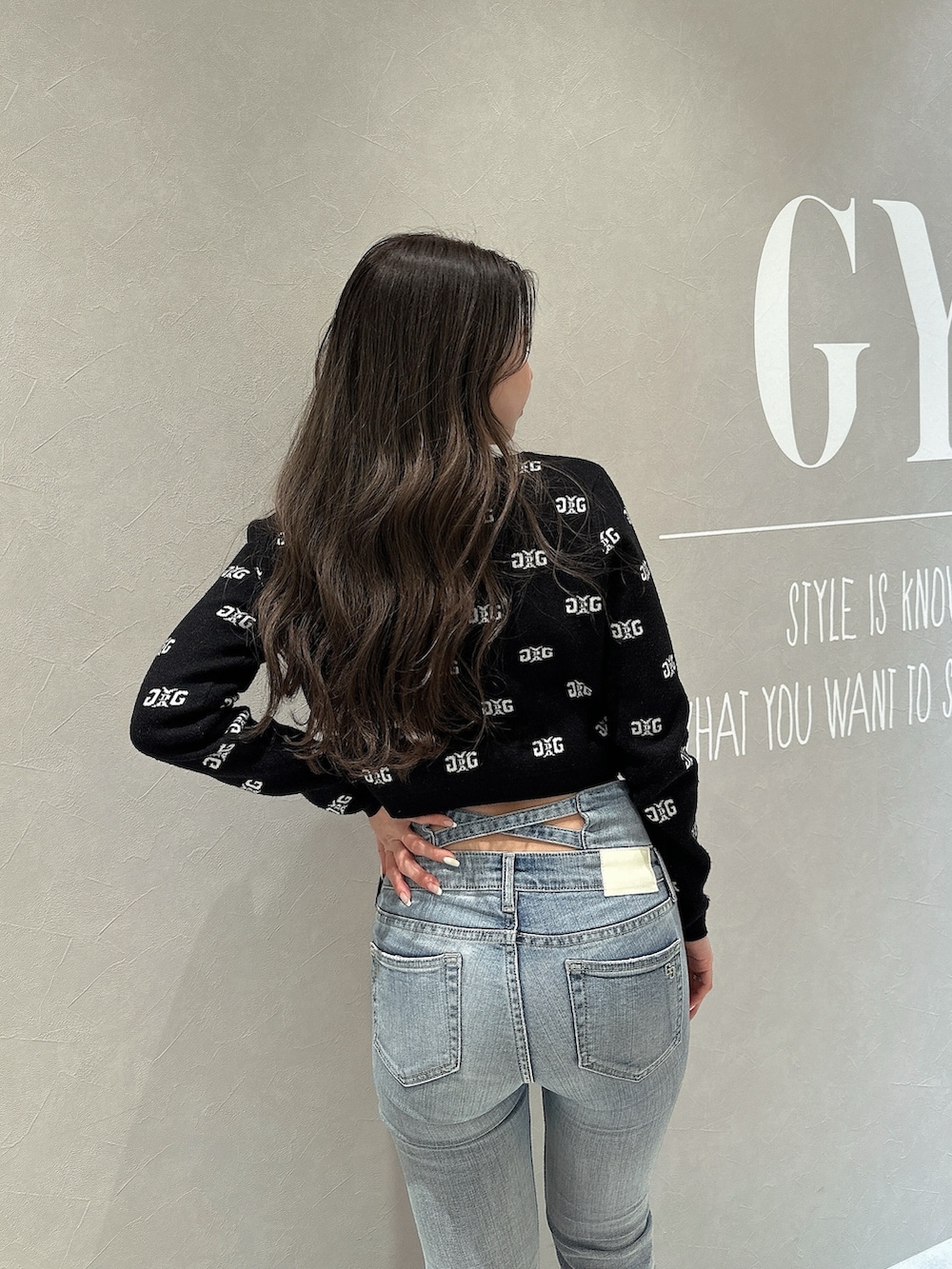 ブラック系のニット/セーター、ブルー系のデニムパンツ、ブラック系のパンプスを着用したレディースの春コーディネートの6枚目の写真
