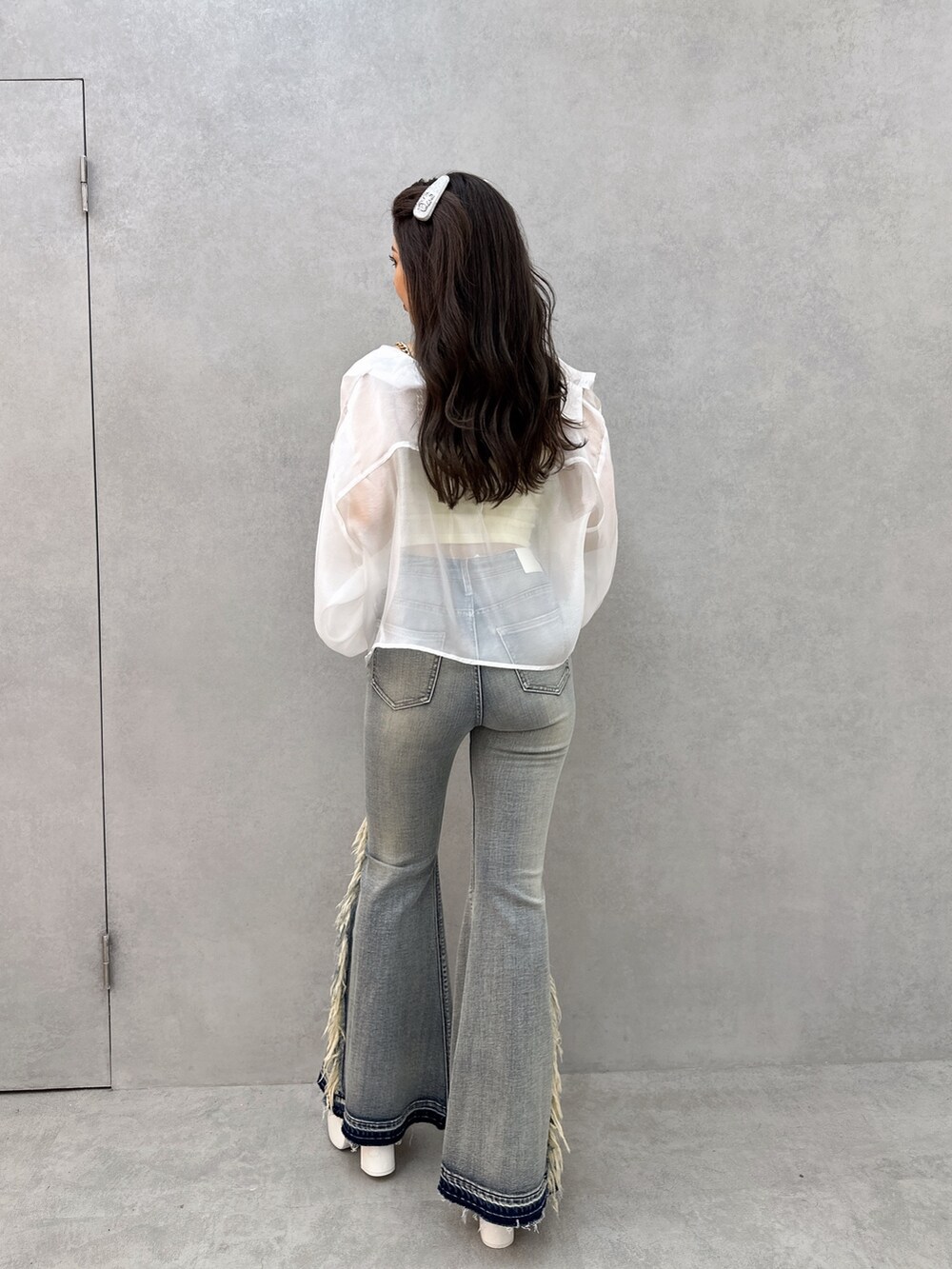 イエロー系のキャミソール、ホワイト系のシャツ/ブラウス、ブルー系のデニムパンツを着用したレディースの春コーディネートの2枚目の写真