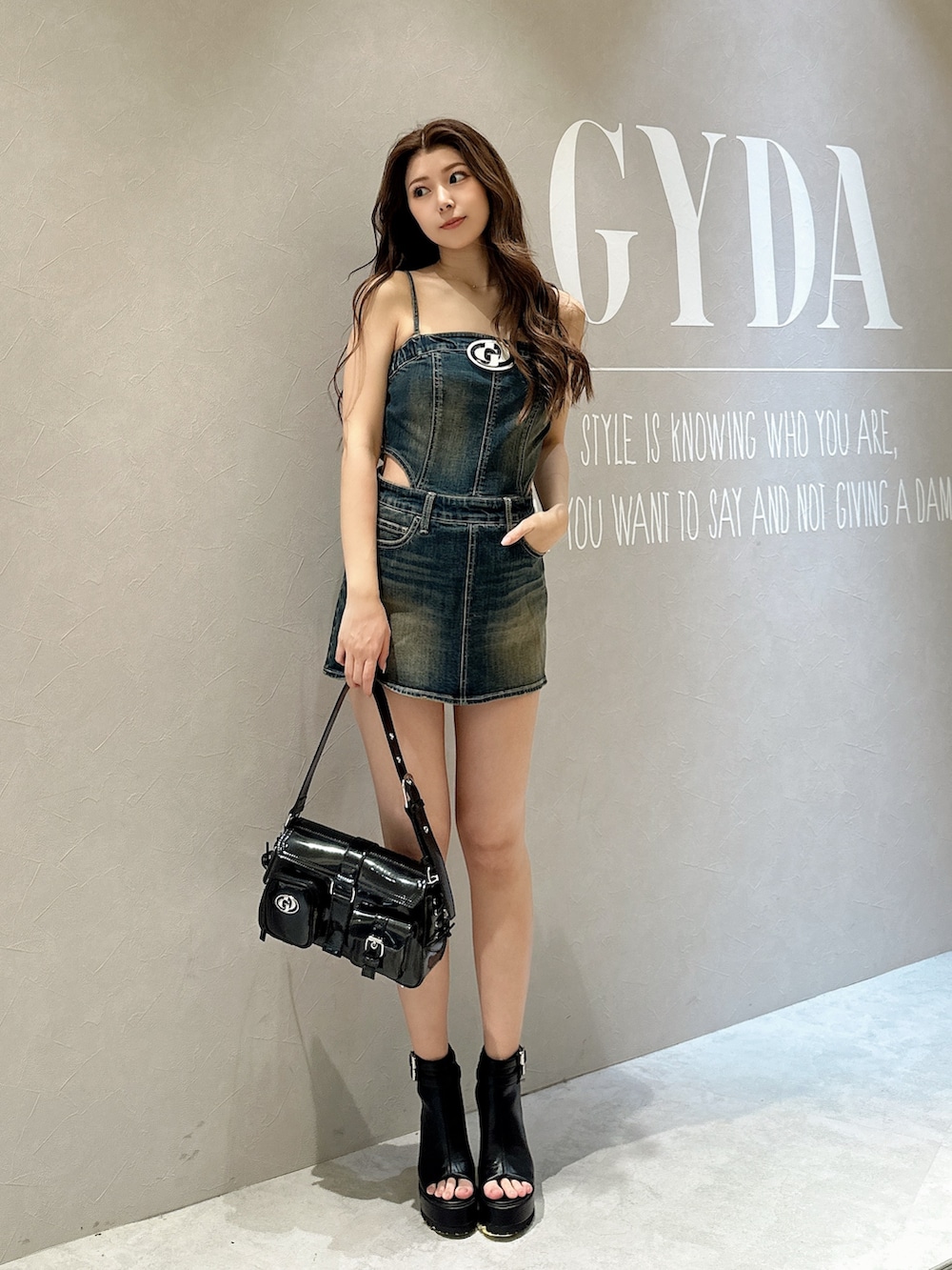 ブラック系のブーツ、ブラック系のハンドバッグ、ブルー系のワンピースを着用したレディースの夏コーディネートの2枚目の写真