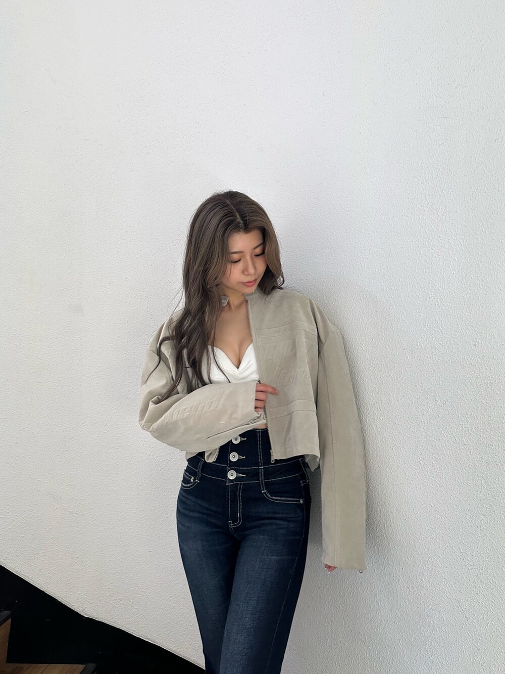 ブラック系のブーツ、ブルー系のデニムパンツ、ホワイト系のチューブトップを着用したレディースの秋コーディネートの3枚目の写真