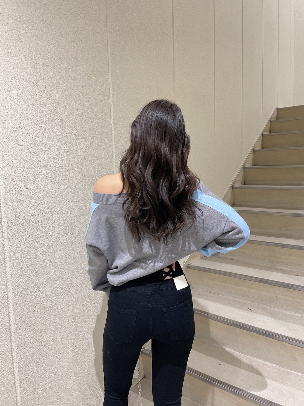 グレー系のニット/セーター、ブラック系のデニムパンツ、ホワイト系のパンプスを着用したレディースの冬コーディネートの6枚目の写真