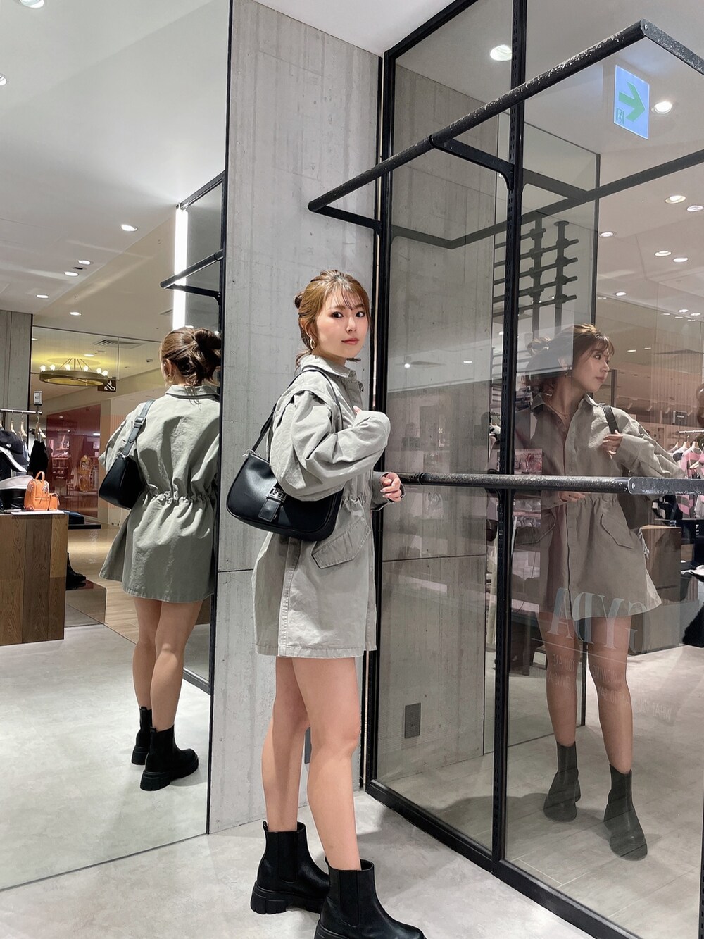 グレー系のミリタリージャケット、ホワイト系のハンドバッグ、ブラック系のブーツを着用したレディースの春コーディネートの3枚目の写真