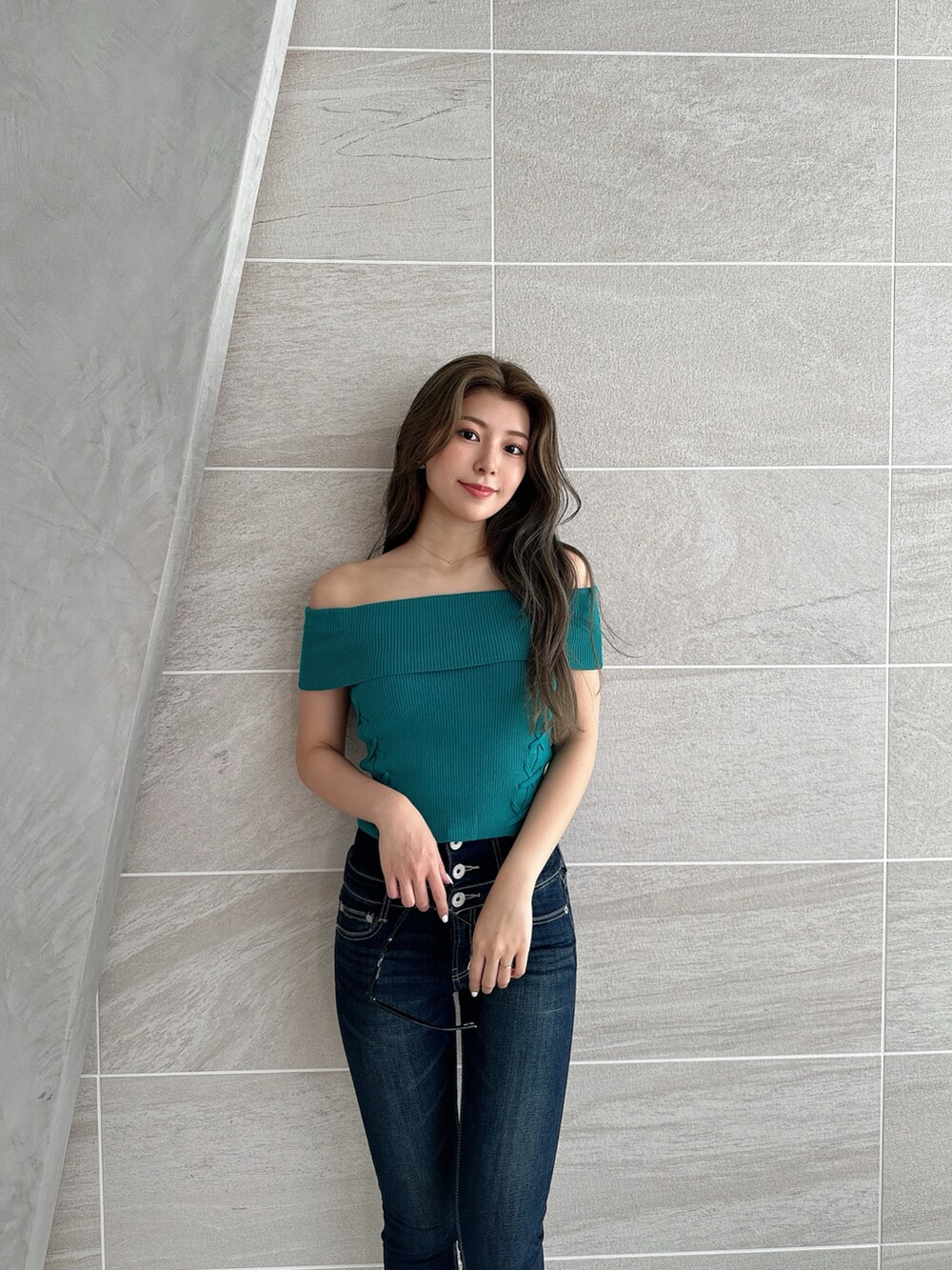 グリーン系のニット/セーター、ホワイト系のパンプス、ブルー系のデニムパンツを着用したレディースの夏コーディネートの5枚目の写真