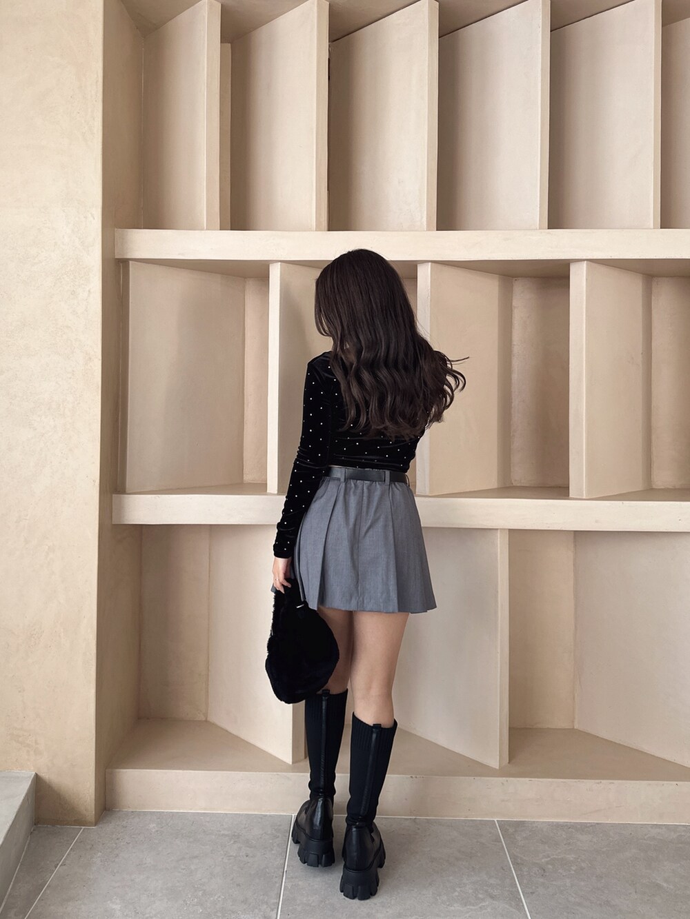 ブラック系のブーツ、ブラック系のTシャツ/カットソー、グレー系のスカートを着用したレディースの秋コーディネートの4枚目の写真