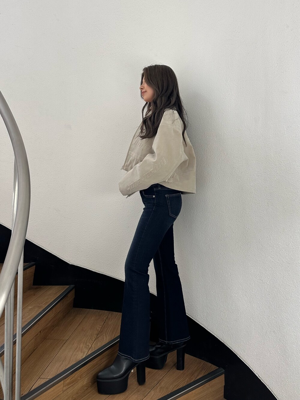 ブラック系のブーツ、ブルー系のデニムパンツ、ホワイト系のチューブトップを着用したレディースの秋コーディネートの2枚目の写真