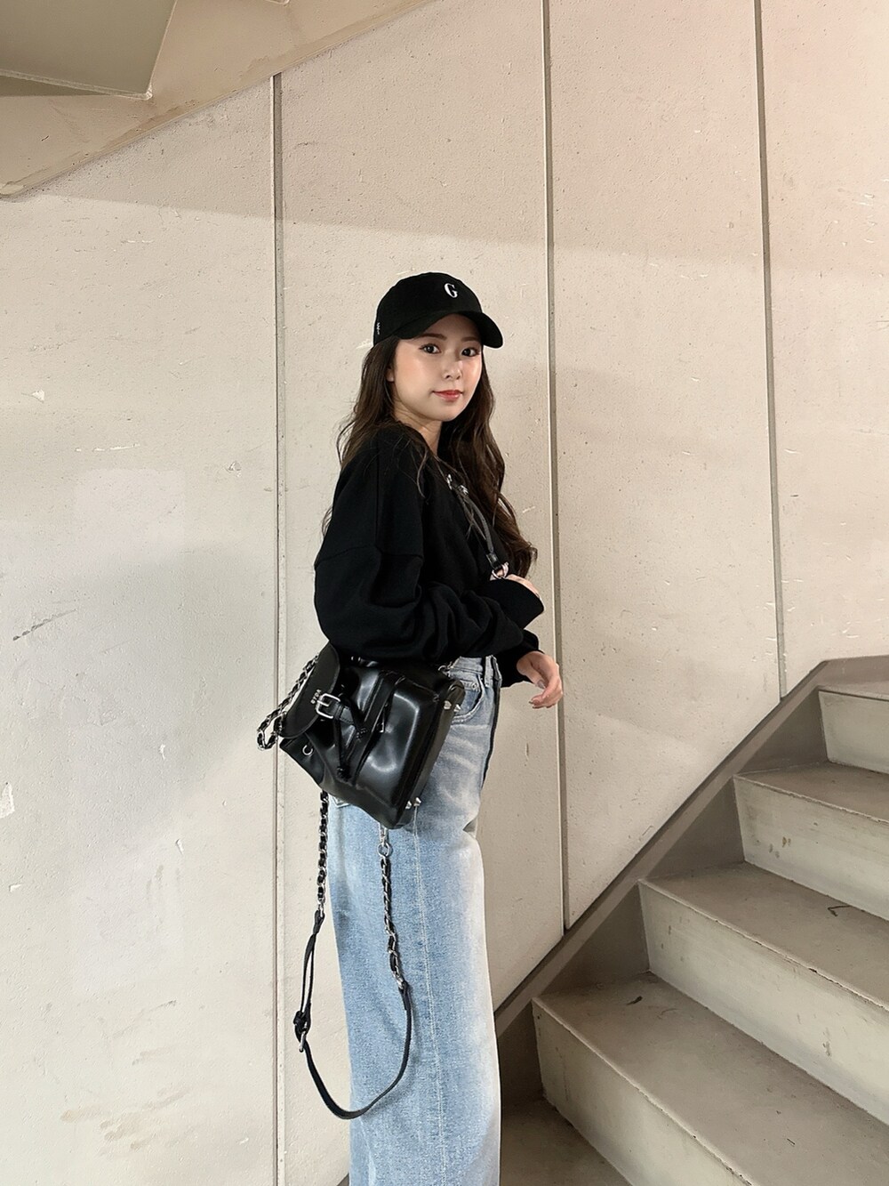 ブラック系のスウェット、ブルー系のデニムパンツ、ブラック系のバックパック/リュックを着用したレディースの冬コーディネートの6枚目の写真