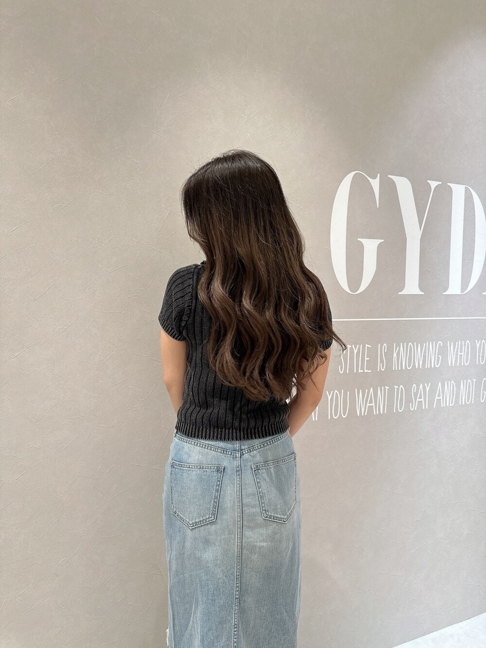 ブルー系のデニムスカート、ホワイト系のサンダル、ブラック系のニット/セーターを着用したレディースの夏コーディネートの5枚目の写真