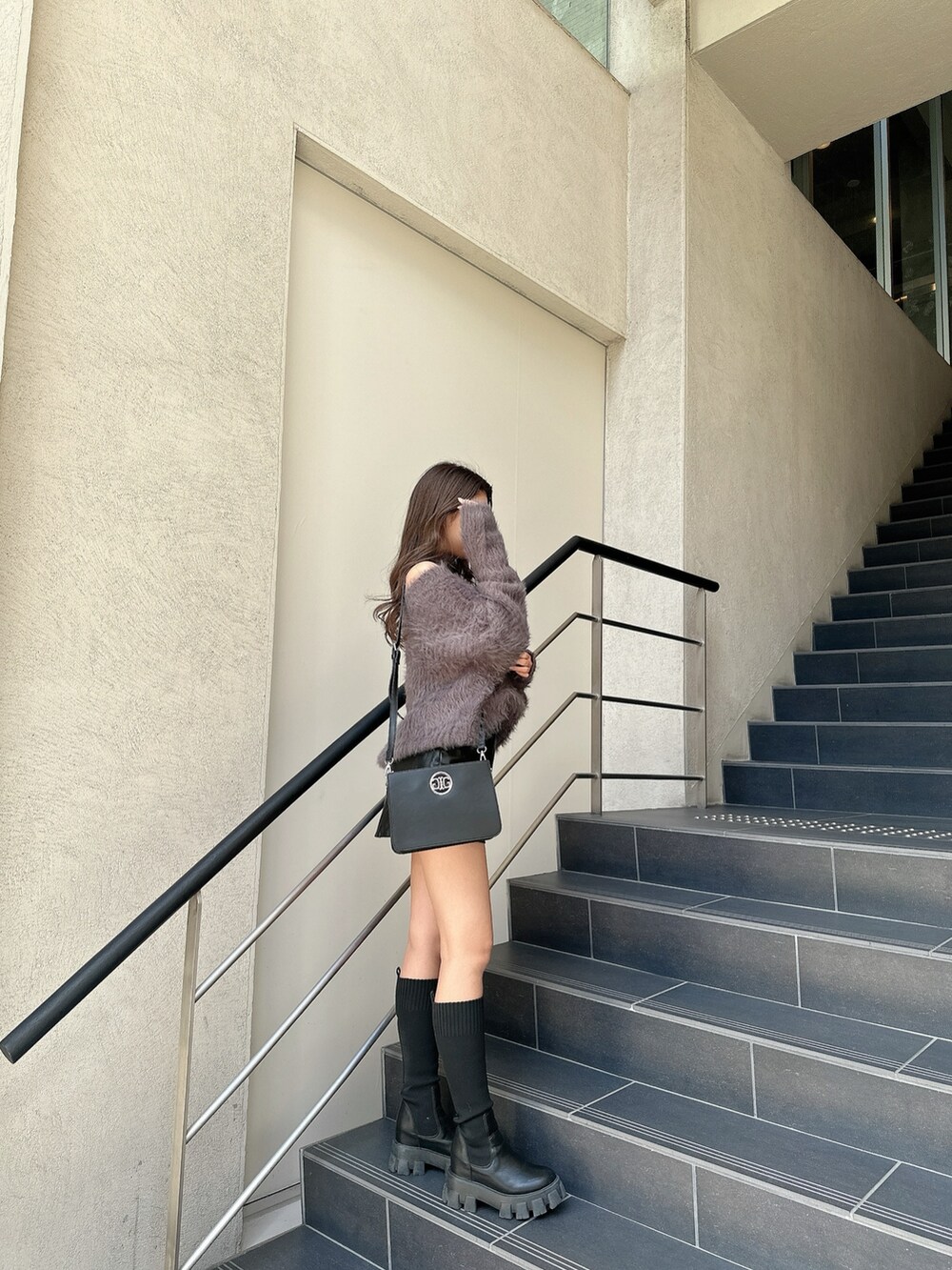 ホワイト系のニット/セーター、ブラック系のスカート、ブラック系のブーツを着用したレディースの冬コーディネートの2枚目の写真