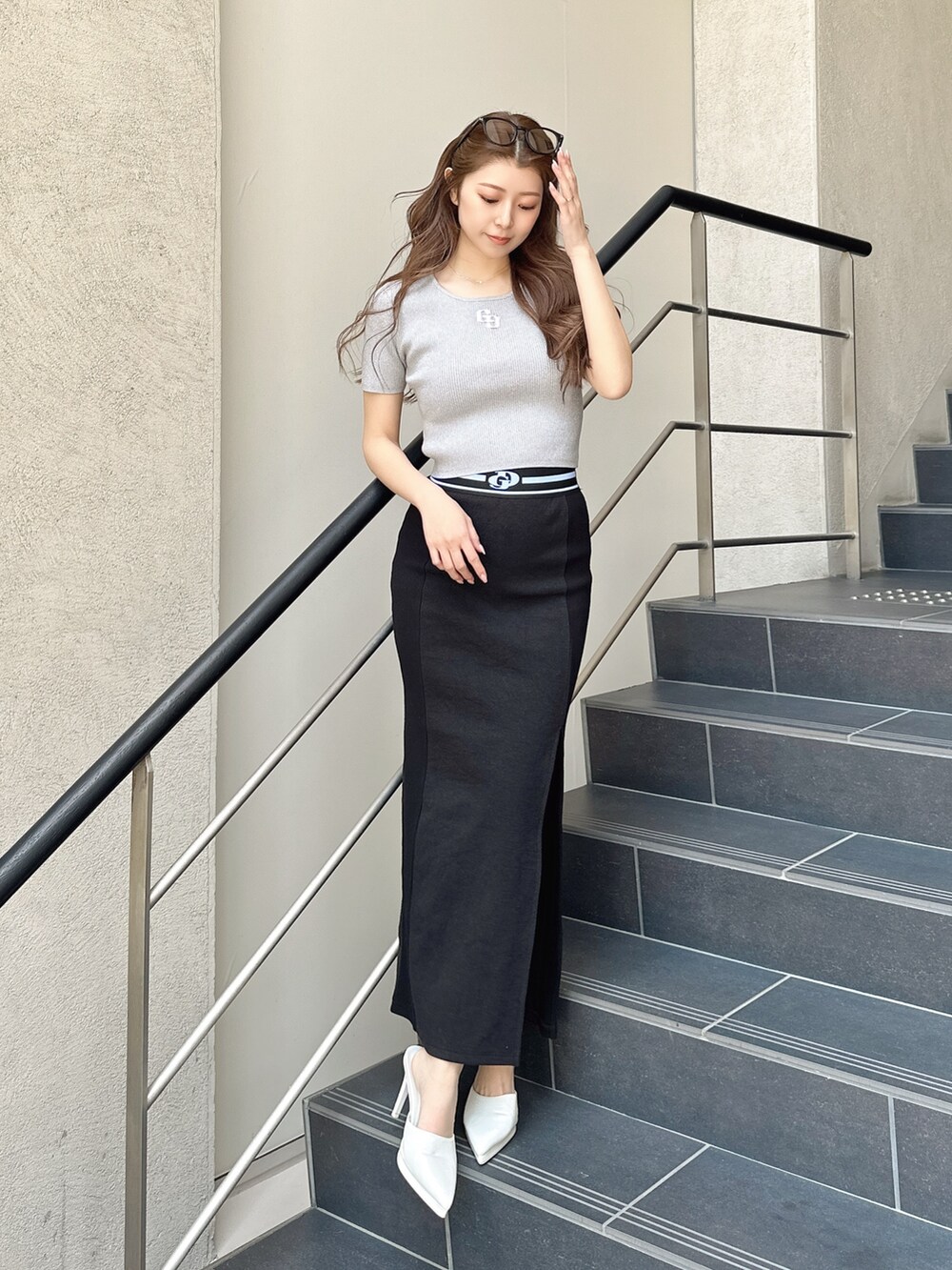 ホワイト系のパンプス、ブラック系のスカート、シルバー系のニット/セーターを着用したレディースの春コーディネートの2枚目の写真