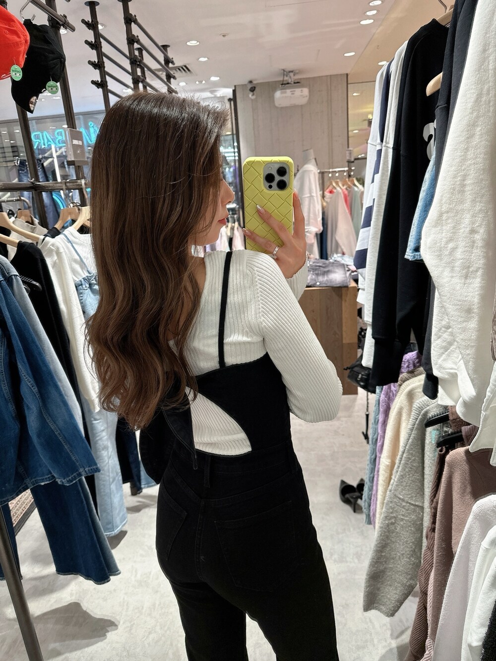 ブラック系のサロペット/オーバーオール、ホワイト系のニット/セーター、ブラック系のパンプスを着用したレディースの春コーディネートの6枚目の写真