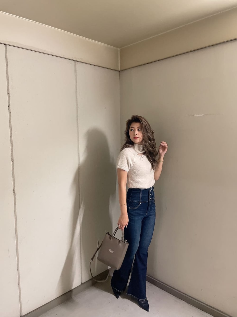 ブラック系のパンプス、ブルー系のデニムパンツ、ベージュ系のショルダーバッグを着用したレディースの夏コーディネートの2枚目の写真