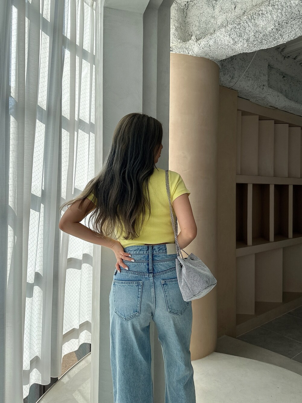 イエロー系のTシャツ/カットソー、シルバー系のショルダーバッグ、ブルー系のデニムパンツを着用したレディースの夏コーディネートの6枚目の写真