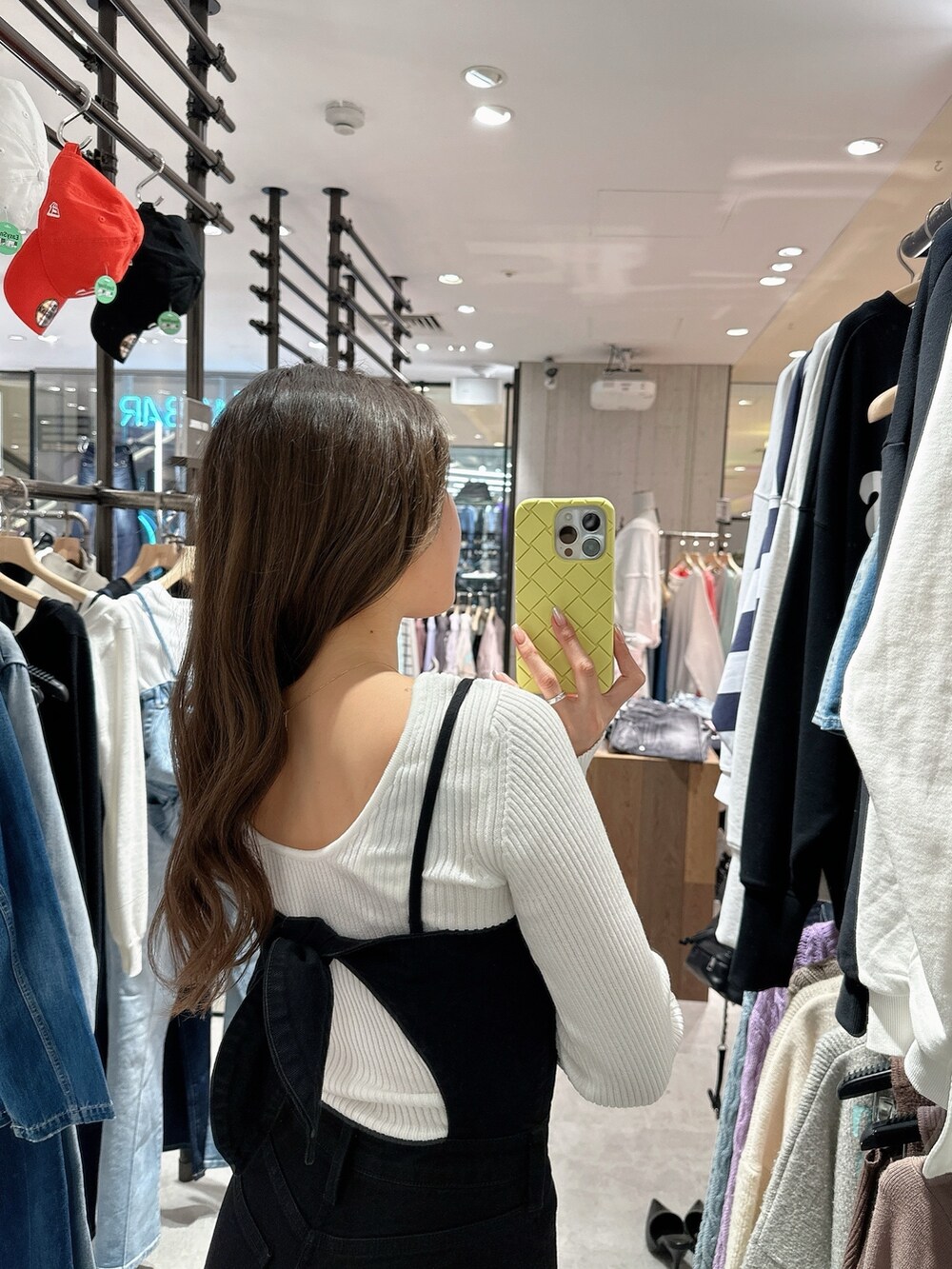 ブラック系のサロペット/オーバーオール、ホワイト系のニット/セーター、ブラック系のパンプスを着用したレディースの春コーディネートの5枚目の写真