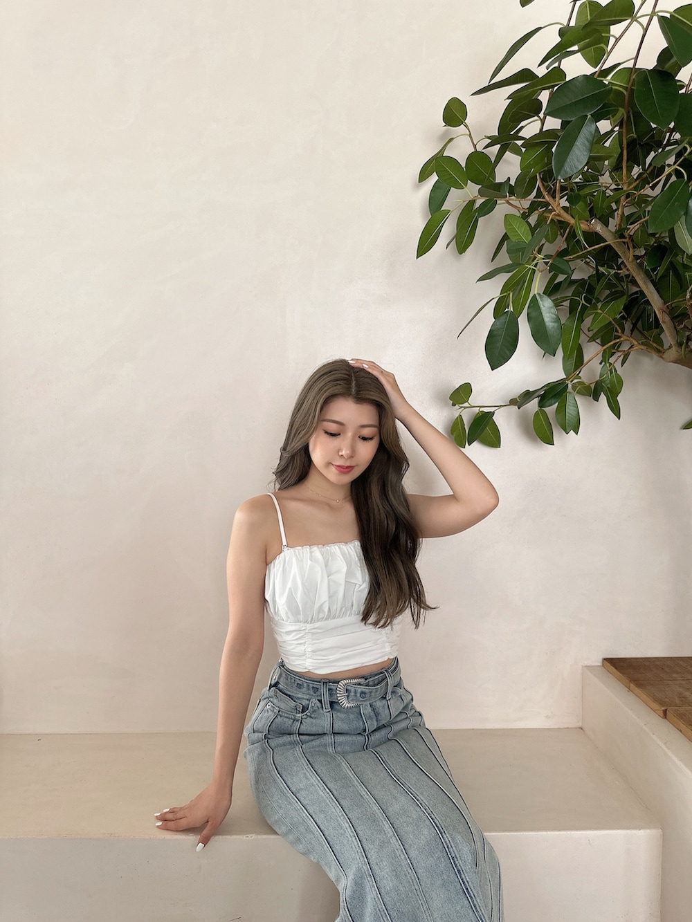 ブルー系のデニムスカート、ホワイト系のキャミソール、ホワイト系のパンプスを着用したレディースの夏コーディネートの2枚目の写真