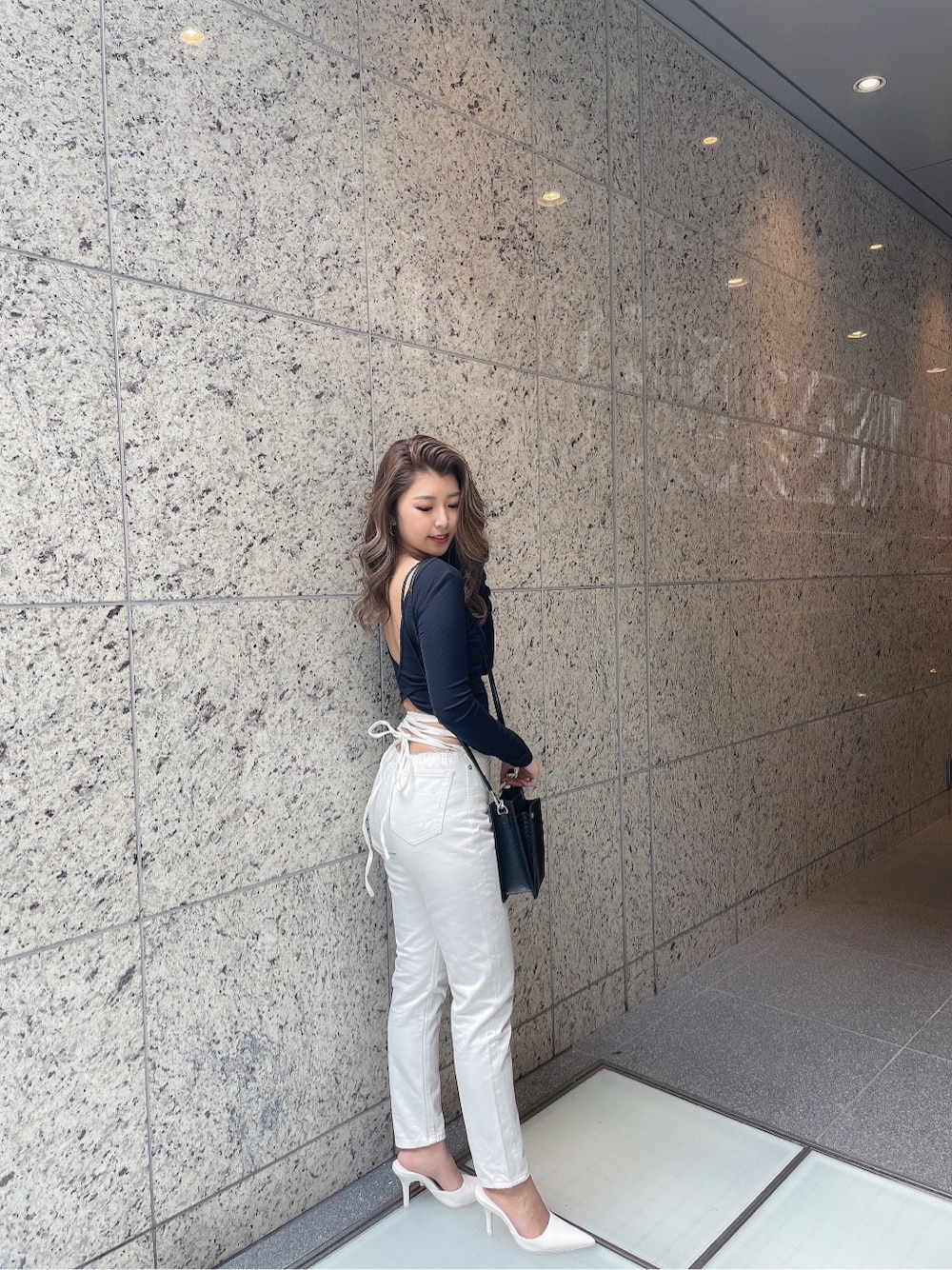 ホワイト系のパンプス、ホワイト系のデニムパンツ、ゴールド系のピアス(両耳用)を着用したレディースの冬コーディネートの3枚目の写真