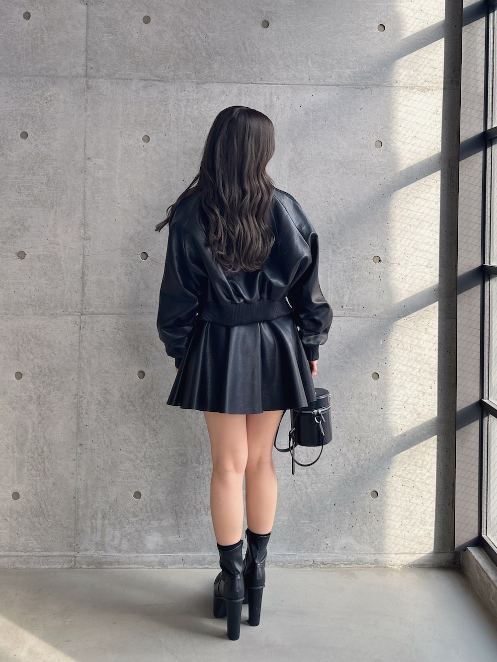 ブラック系のブーツ、ブラック系のスカート、ブラック系のブルゾンを着用したレディースの冬コーディネートの2枚目の写真