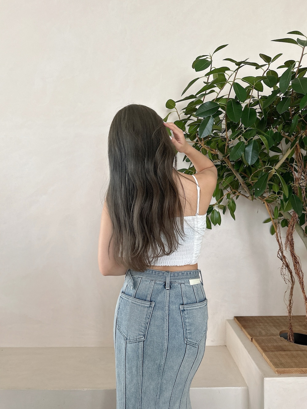 ブルー系のデニムスカート、ホワイト系のキャミソール、ホワイト系のパンプスを着用したレディースの夏コーディネートの3枚目の写真