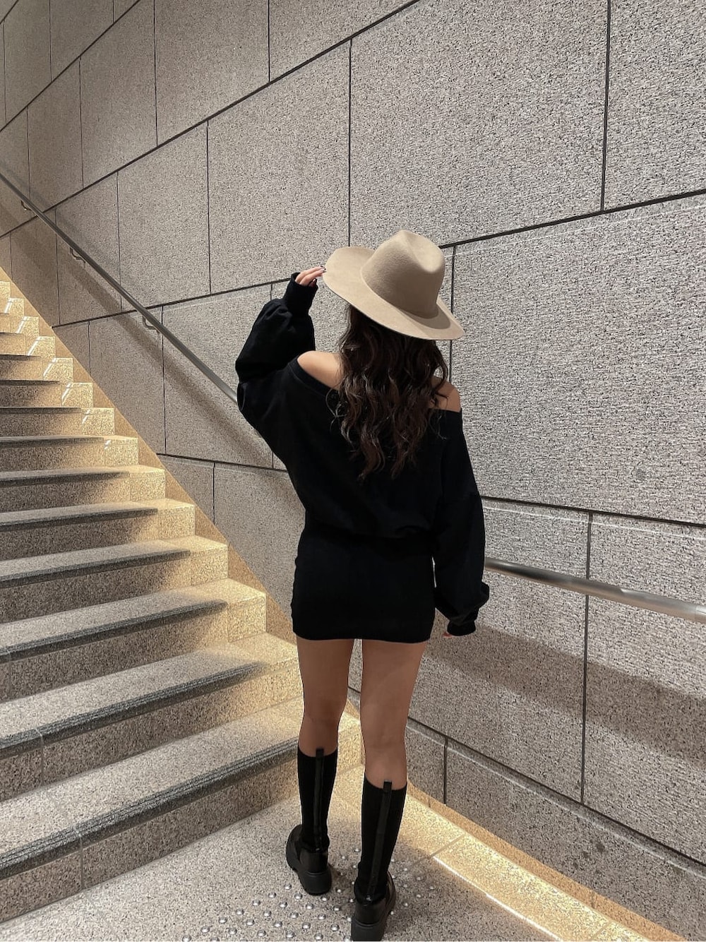 ブラック系のワンピース、ブラック系のブーツ、ベージュ系のハットを着用したレディースの秋コーディネートの4枚目の写真