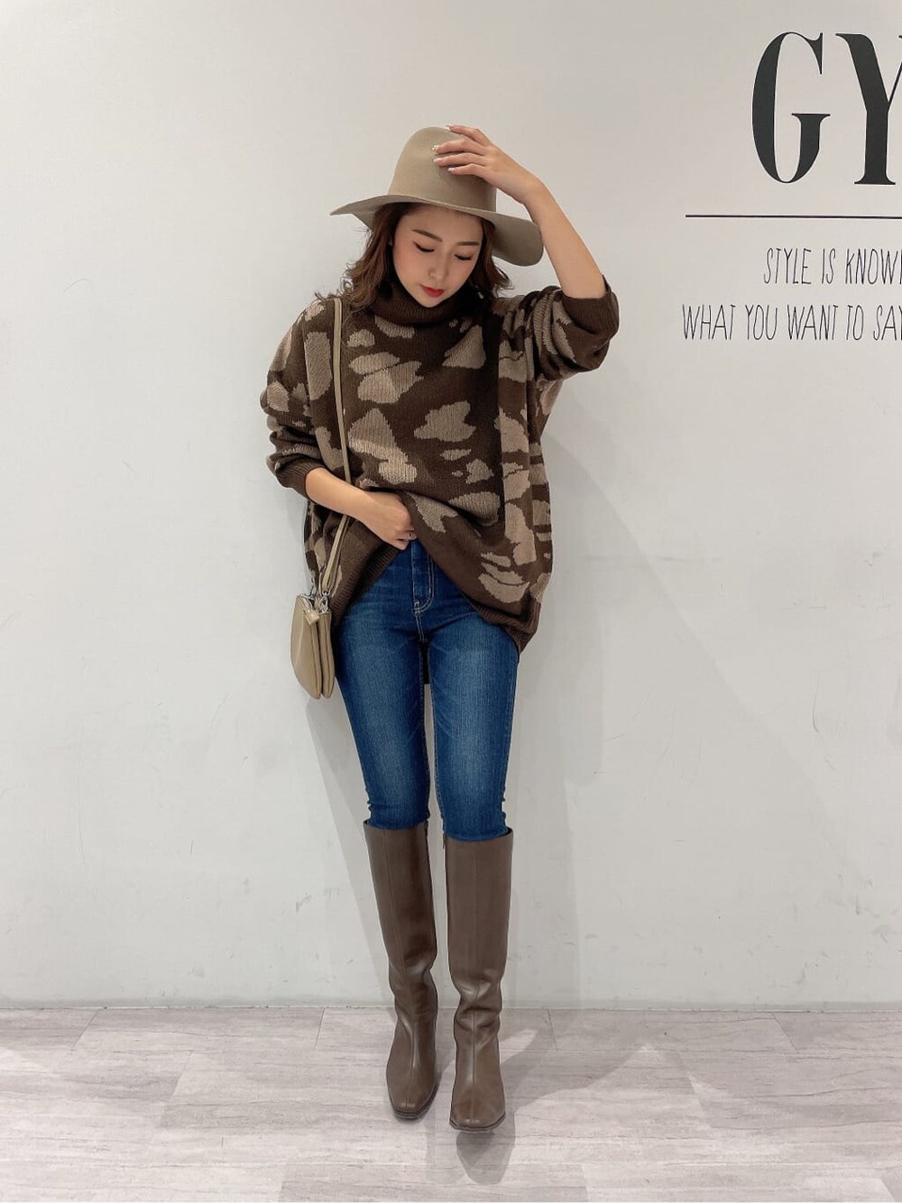 ブラウン系のブーツ、ブルー系のデニムパンツ、ベージュ系のショルダーバッグを着用したレディースの秋コーディネートの4枚目の写真