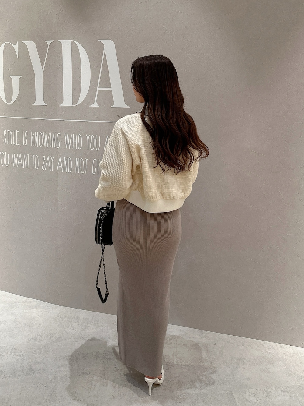 グレー系のワンピース、ホワイト系のブルゾン、ブラック系のハンドバッグを着用したレディースの春コーディネートの3枚目の写真