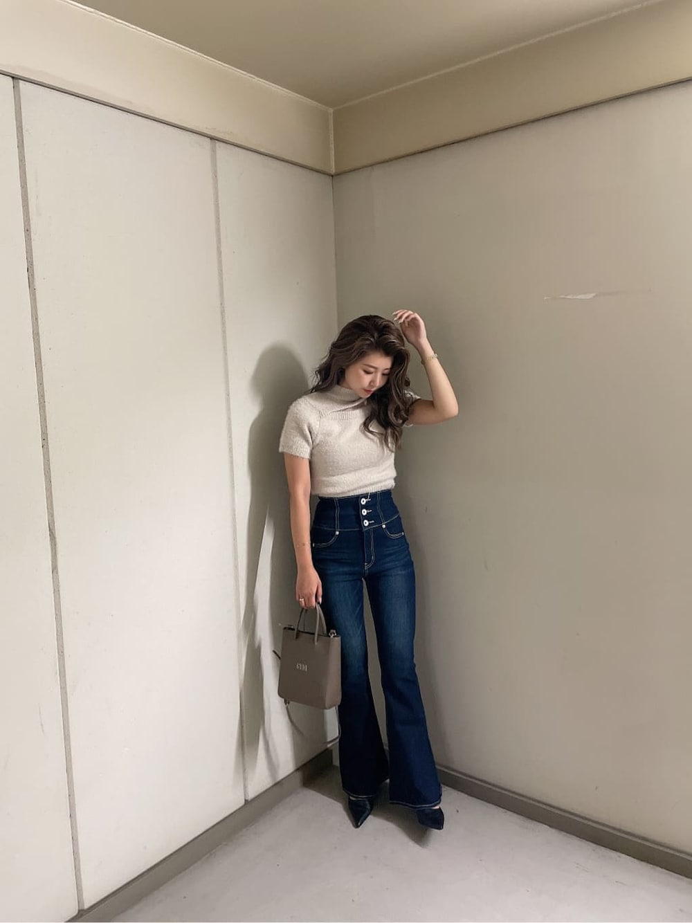 ブラック系のパンプス、ブルー系のデニムパンツ、ベージュ系のショルダーバッグを着用したレディースの夏コーディネートの3枚目の写真