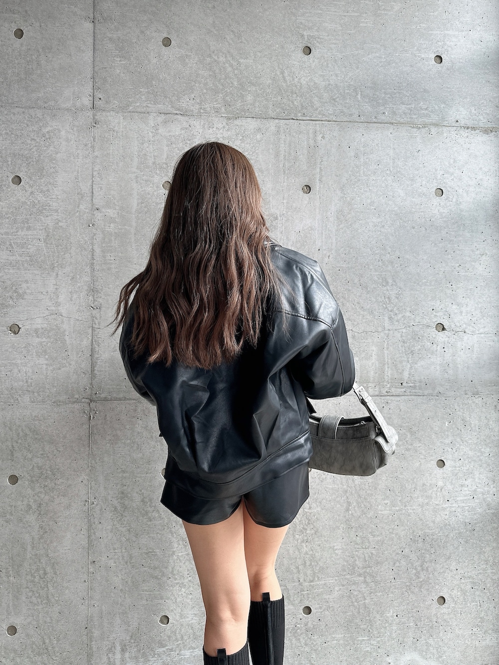 グリーン系のショルダーバッグ、ブラック系のブーツ、ブラック系のニット/セーターを着用したレディースの秋コーディネートの3枚目の写真