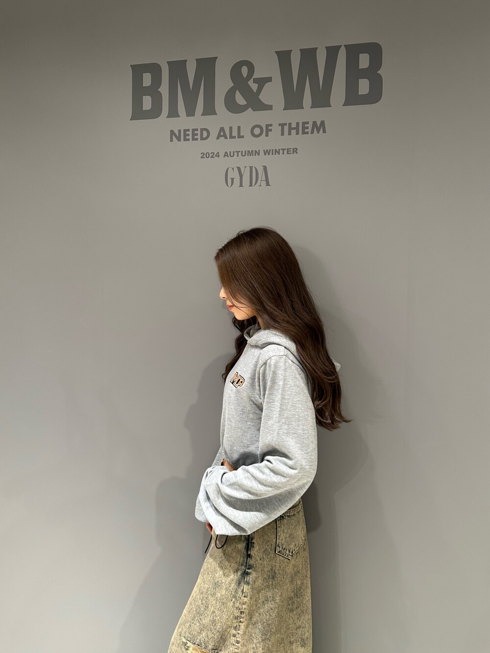 グレー系のパーカー、ブルー系のデニムスカート、ブラック系のブルゾンを着用したレディースの秋コーディネートの6枚目の写真