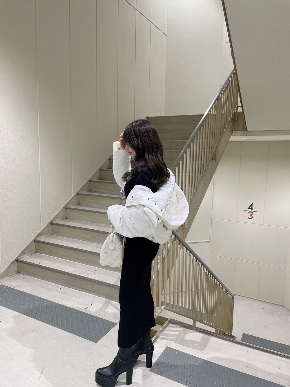 ブラック系のワンピース、ブラック系のダウンジャケット/コート、ブラック系のブーツを着用したレディースの冬コーディネートの2枚目の写真