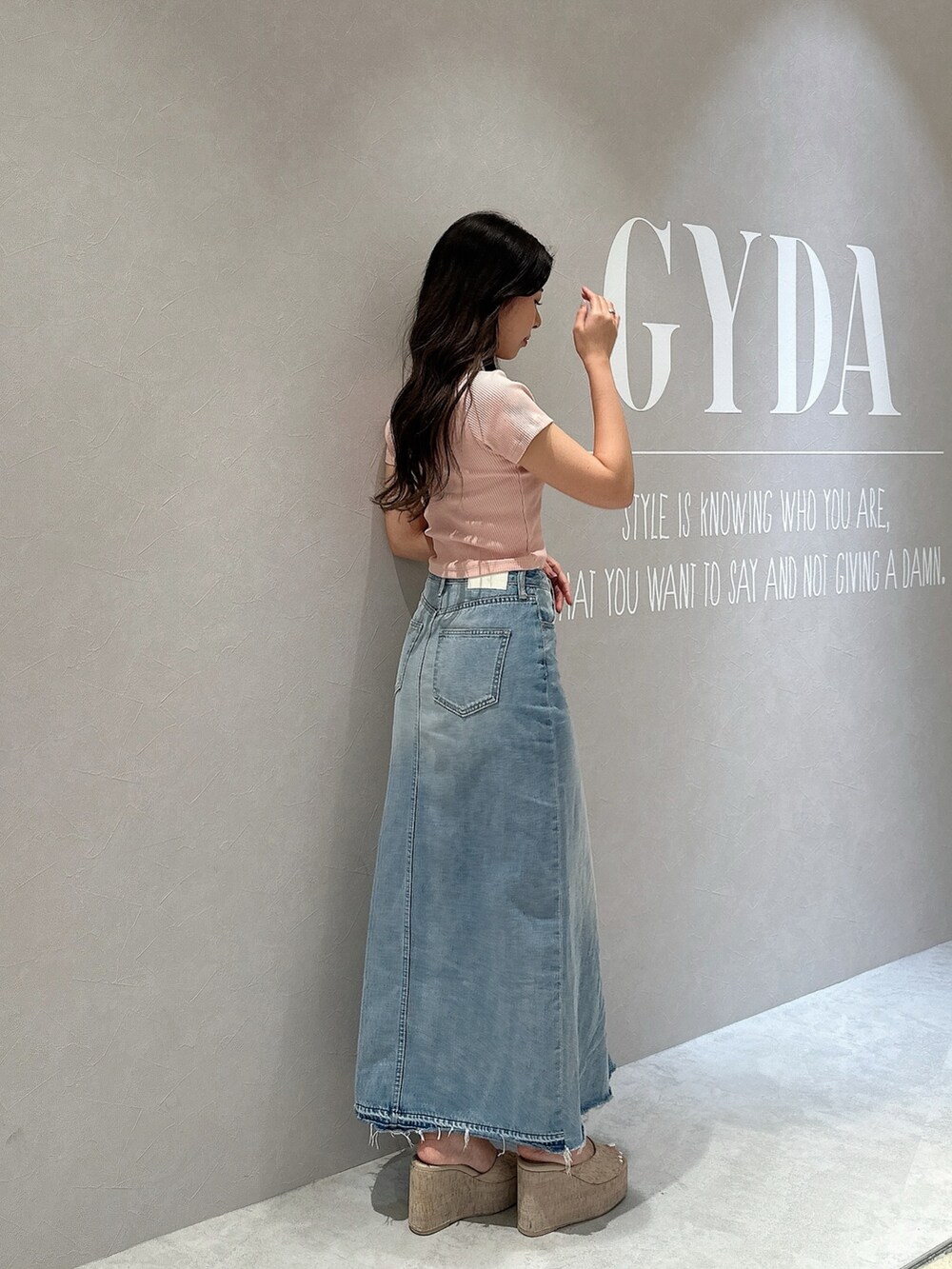 ブルー系のデニムスカート、ホワイト系のサンダル、ピンク系のTシャツ/カットソーを着用したレディースの春コーディネートの2枚目の写真