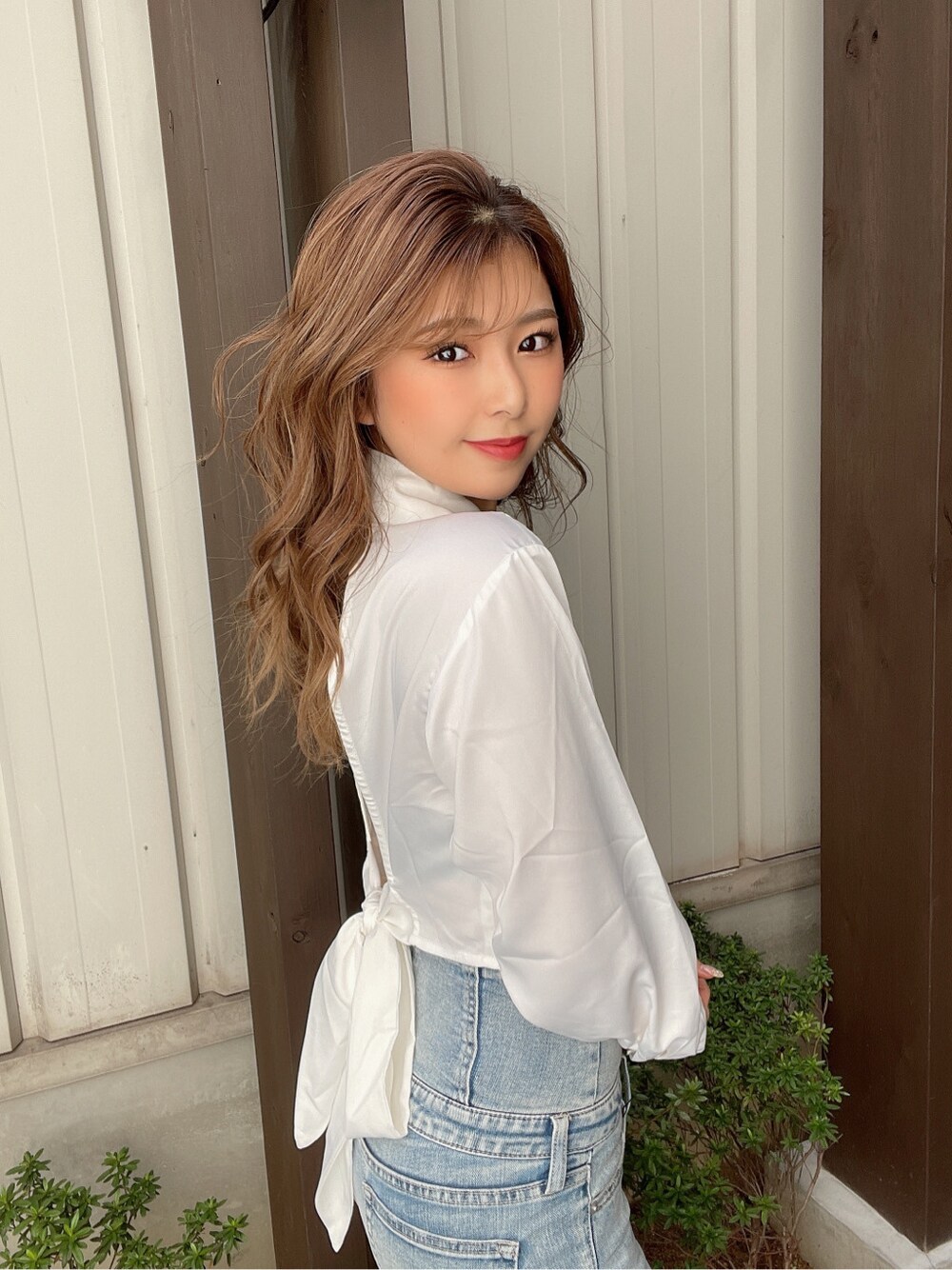 ブルー系のデニムパンツ、ブラック系のチューブトップ、ホワイト系のパンプスを着用したレディースの春コーディネートの2枚目の写真