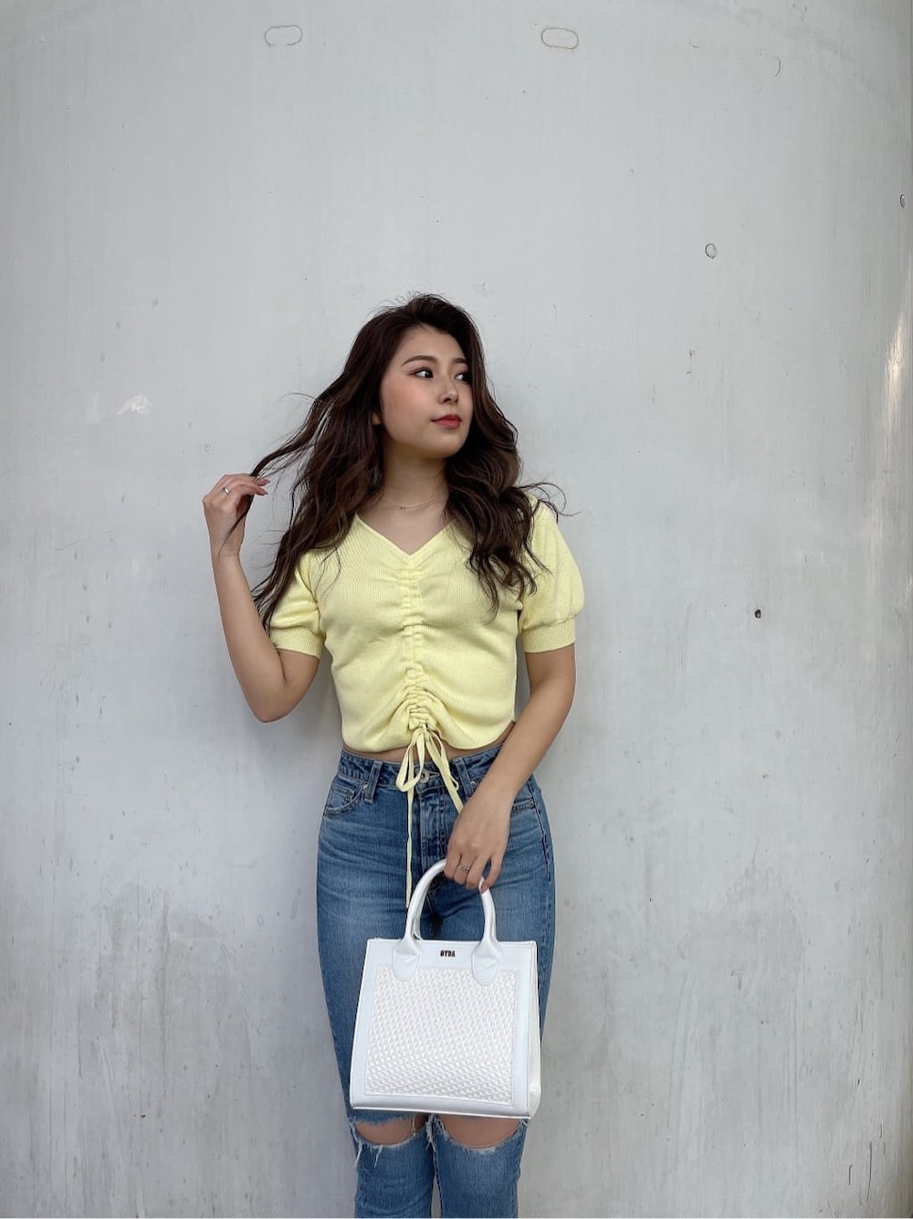 ホワイト系のパンプス、ホワイト系のハンドバッグ、ブルー系のデニムパンツを着用したレディースの春コーディネートの5枚目の写真