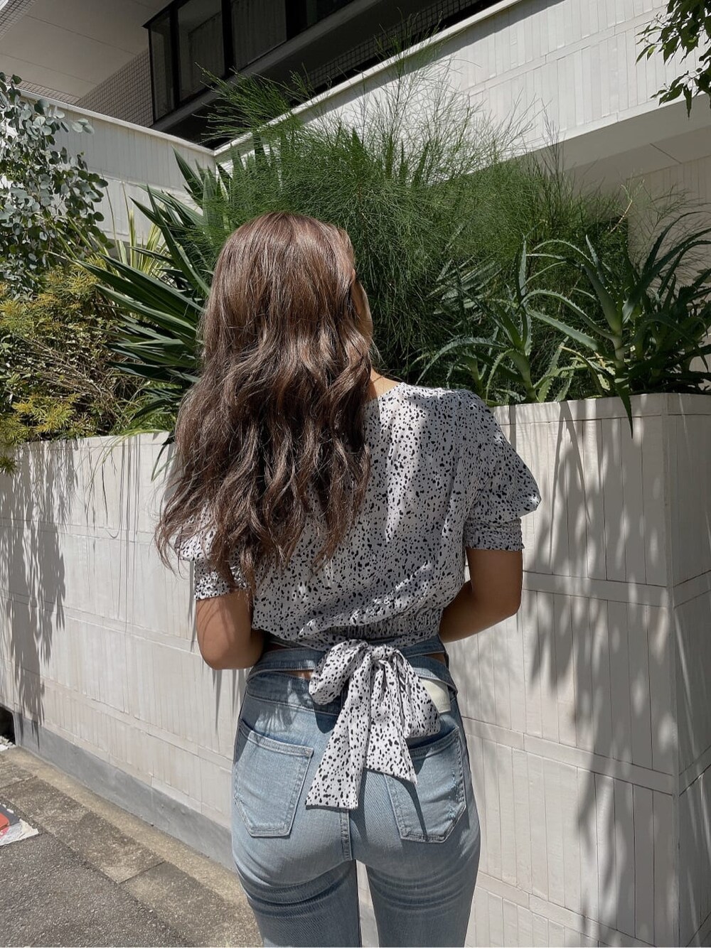 ホワイト系のシャツ/ブラウス、ホワイト系のパンプス、ブルー系のデニムパンツを着用したレディースの夏コーディネートの5枚目の写真