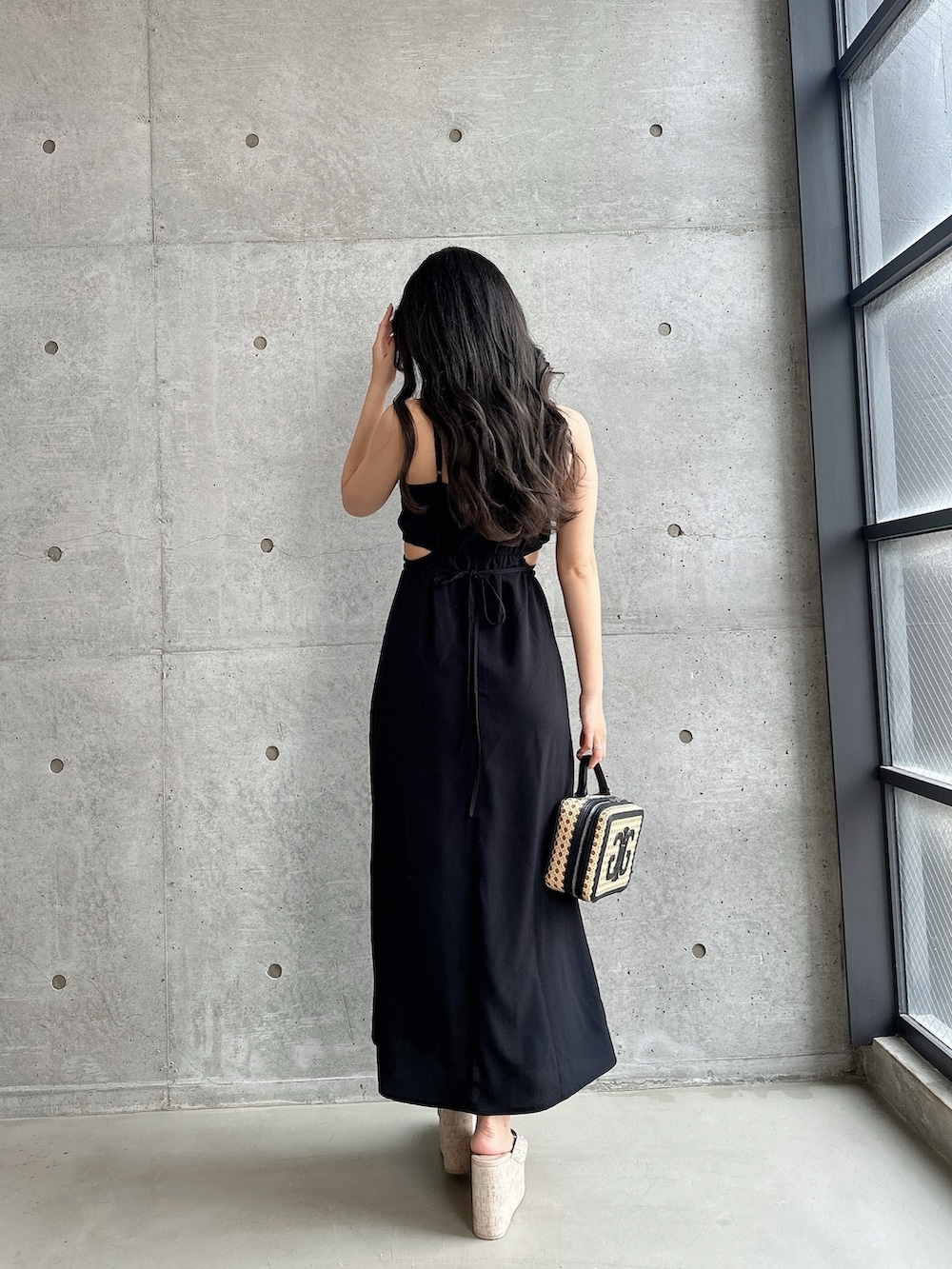 ホワイト系のサンダル、ブラック系のワンピース、ベージュ系のショルダーバッグを着用したレディースの夏コーディネートの3枚目の写真