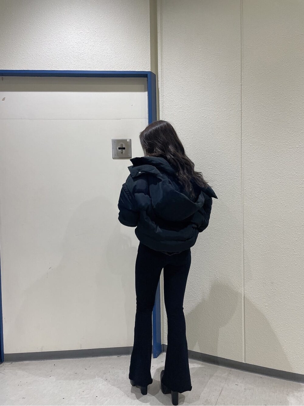 ブラック系のブーツ、ブラック系のダウンジャケット/コート、ホワイト系のニット/セーターを着用したレディースの秋コーディネートの3枚目の写真