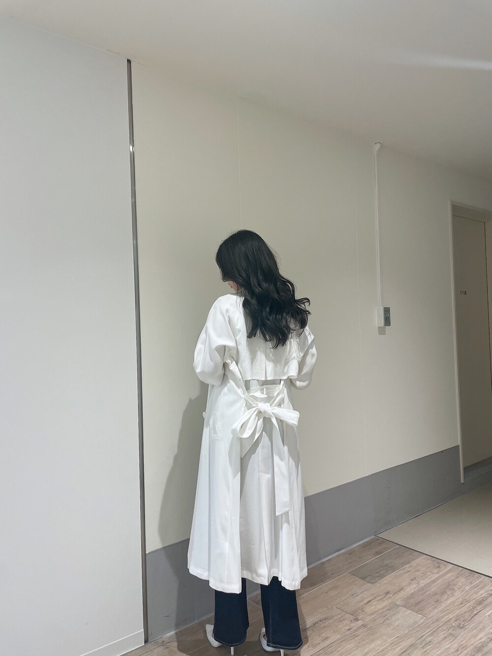 ブルー系のニット/セーター、ホワイト系のトレンチコート、ブルー系のデニムパンツを着用したレディースの春コーディネートの3枚目の写真