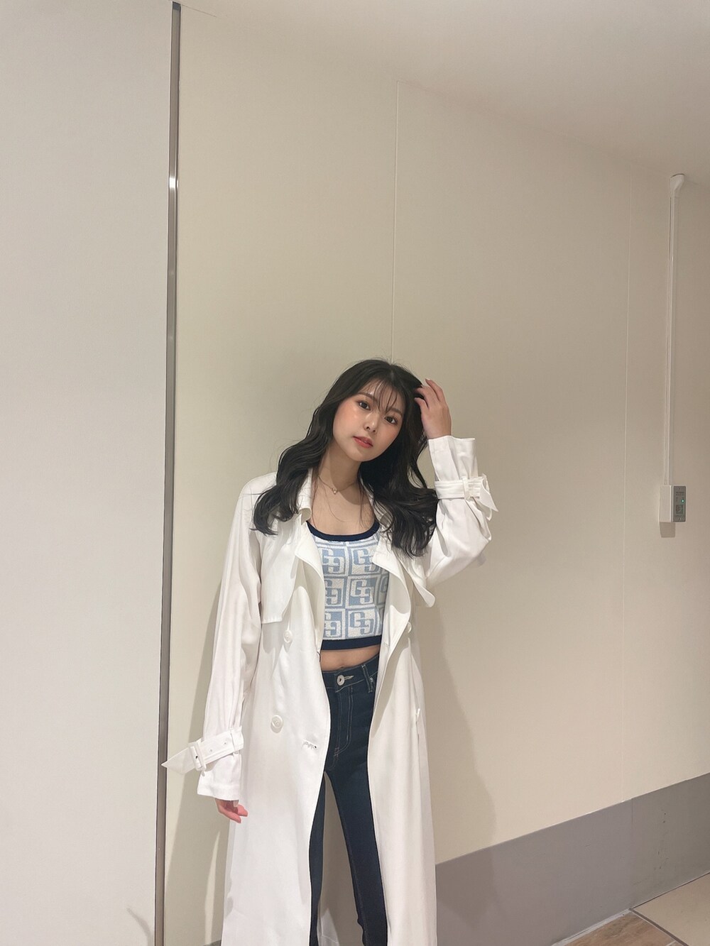 ブルー系のニット/セーター、ホワイト系のトレンチコート、ブルー系のデニムパンツを着用したレディースの春コーディネートの6枚目の写真