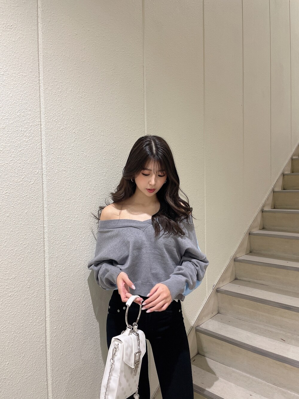 グレー系のニット/セーター、ブラック系のデニムパンツ、ホワイト系のパンプスを着用したレディースの冬コーディネートの5枚目の写真