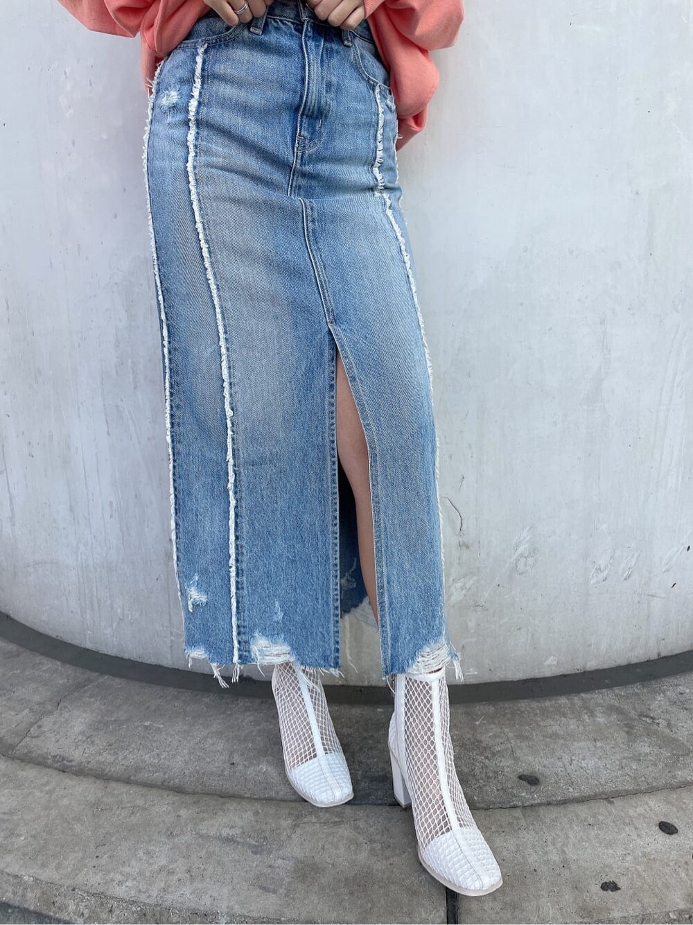 ホワイト系のブーツ、オレンジ系のスウェット、ブルー系のデニムスカートを着用したレディースの冬コーディネートの8枚目の写真